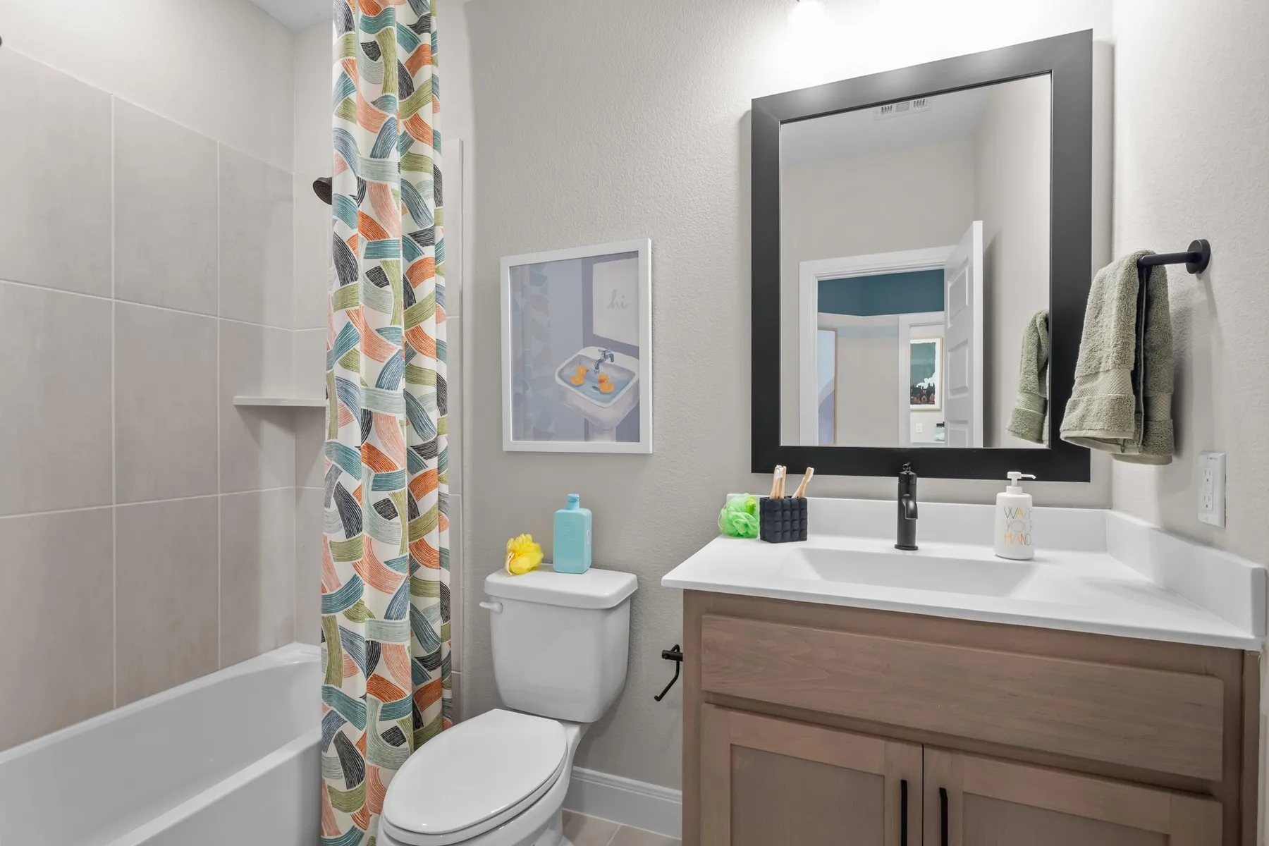 Full bath featuring vanity, shower / bath combo, and a textured wall