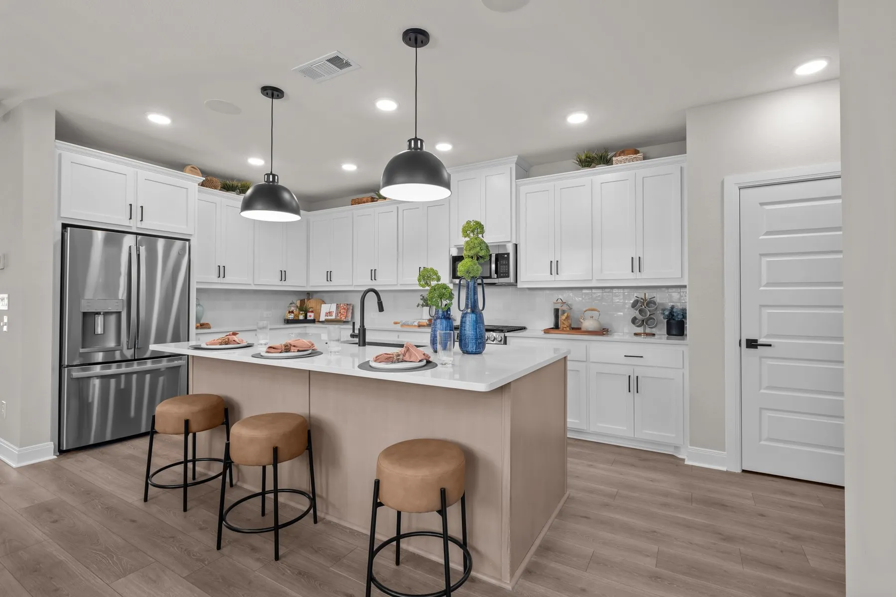Kitchen with stainless steel appliances, a kitchen breakfast bar, an island with sink, light wood-type flooring, and two tone cabinetry