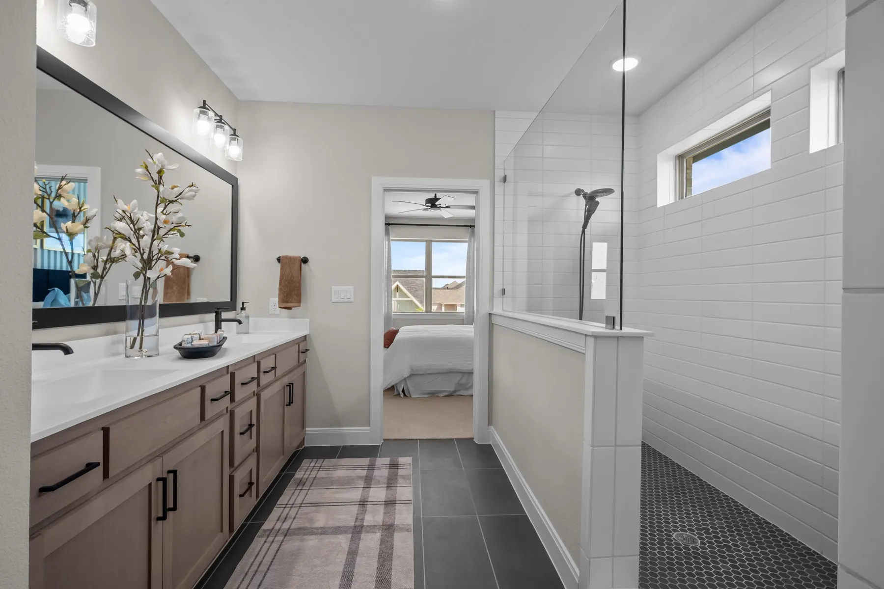 Bathroom featuring connected bathroom, healthy amount of natural light, double vanity, and dark tile patterned floors