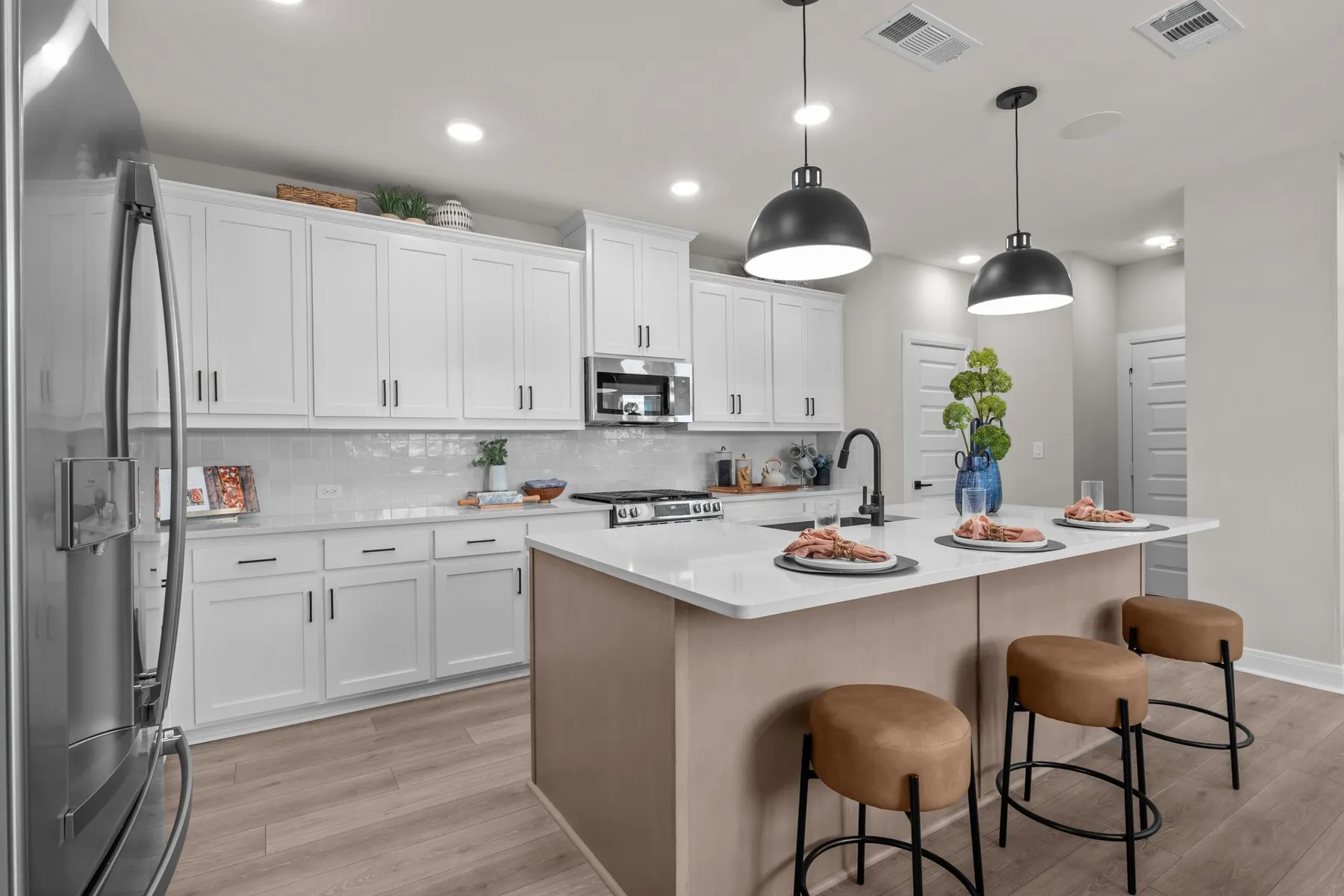 Kitchen with stainless steel appliances, a breakfast bar area, a kitchen island with sink, light wood-style floors, and dual tone cabinets