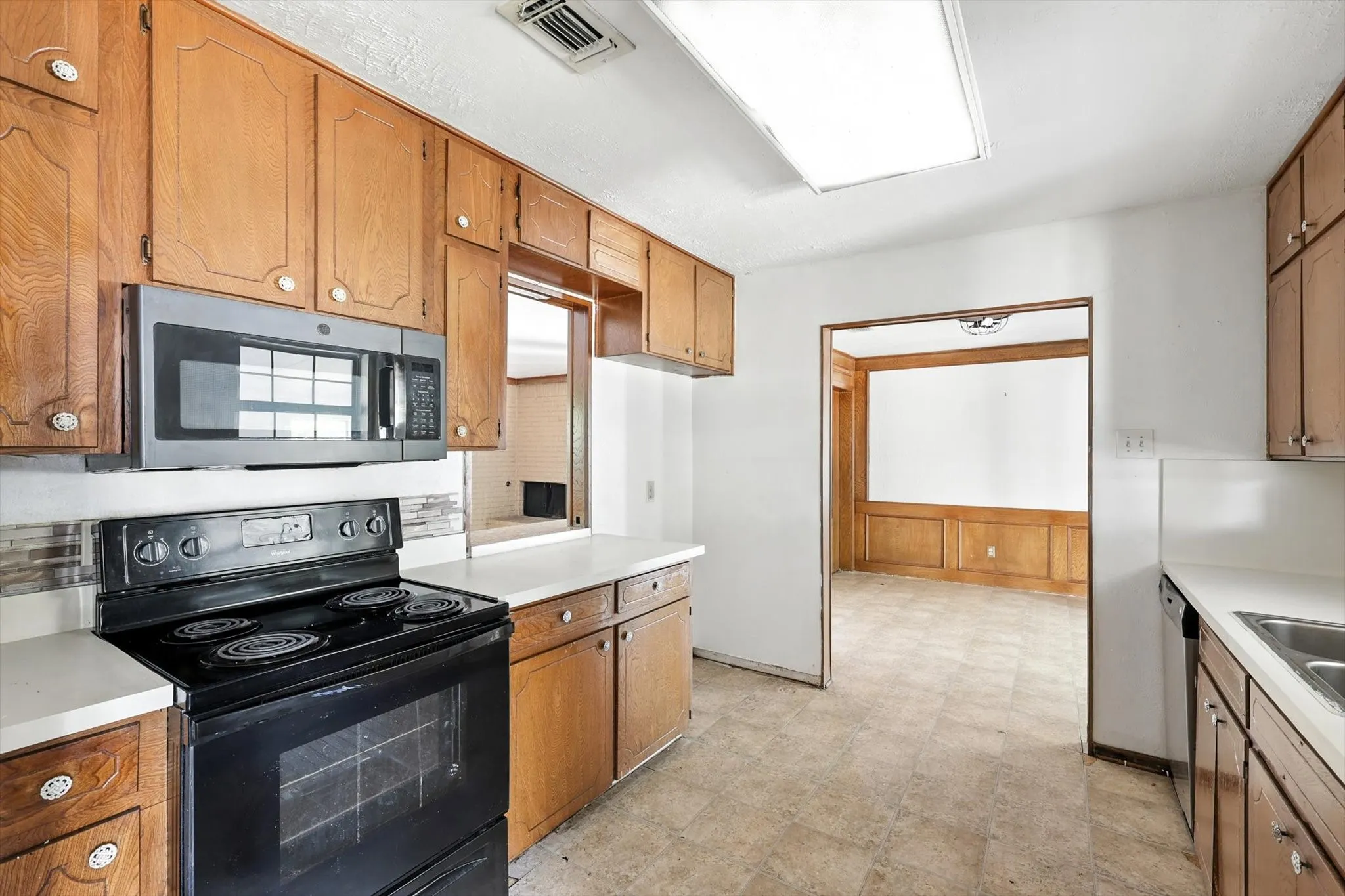 Kitchen with appliances with stainless steel finishes, light countertops, brown cabinetry, and backsplash
