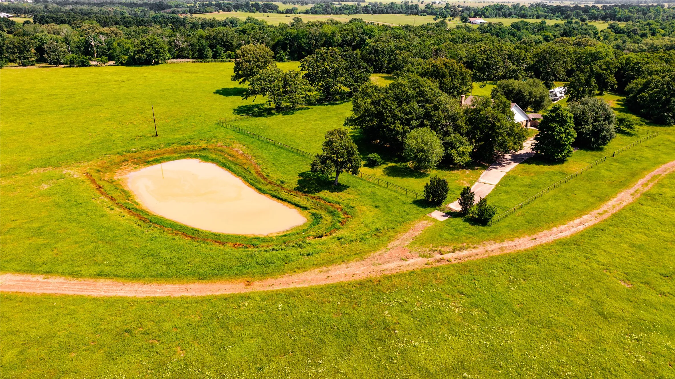Expansive green acreage featuring a large pond and mature trees
