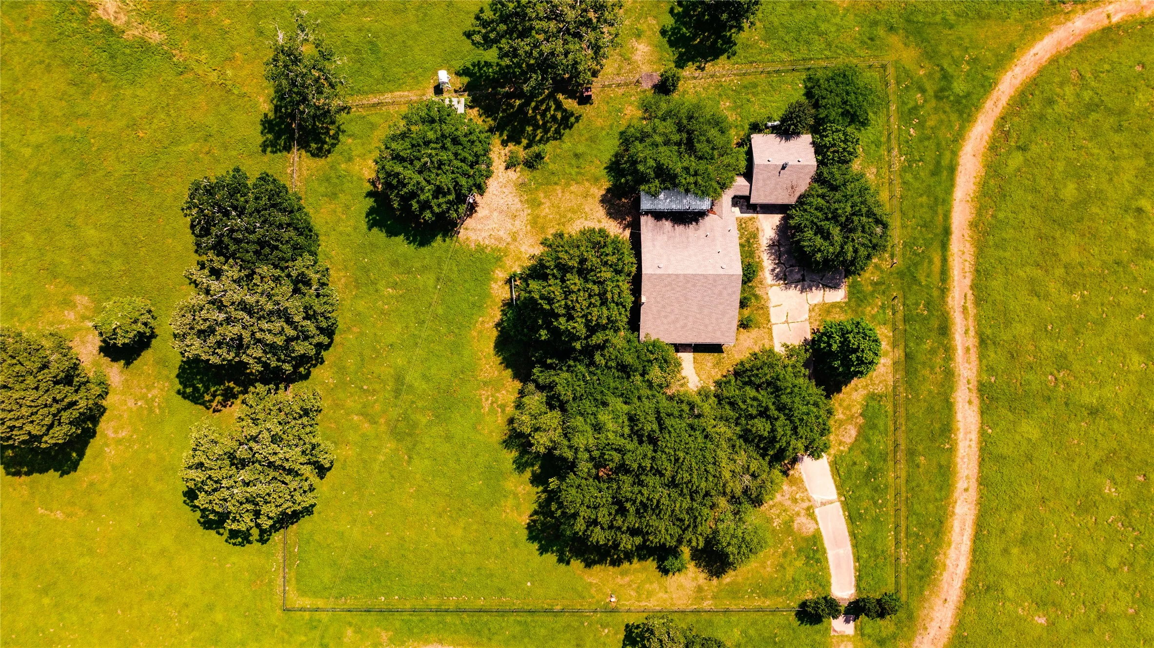 Expansive property featuring a main residence with an attached structure, surrounded by mature trees and lush green acreage