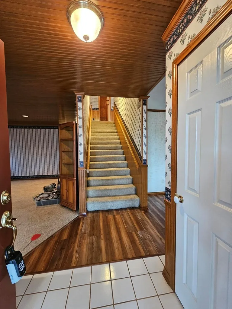 Stairway with tile patterned floors, wallpapered walls, and wood ceiling