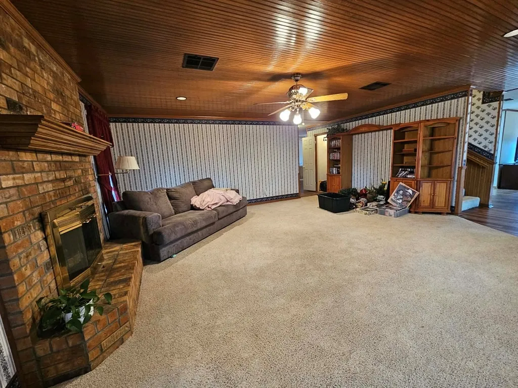 Living room featuring a fireplace, carpet floors, and ceiling fan