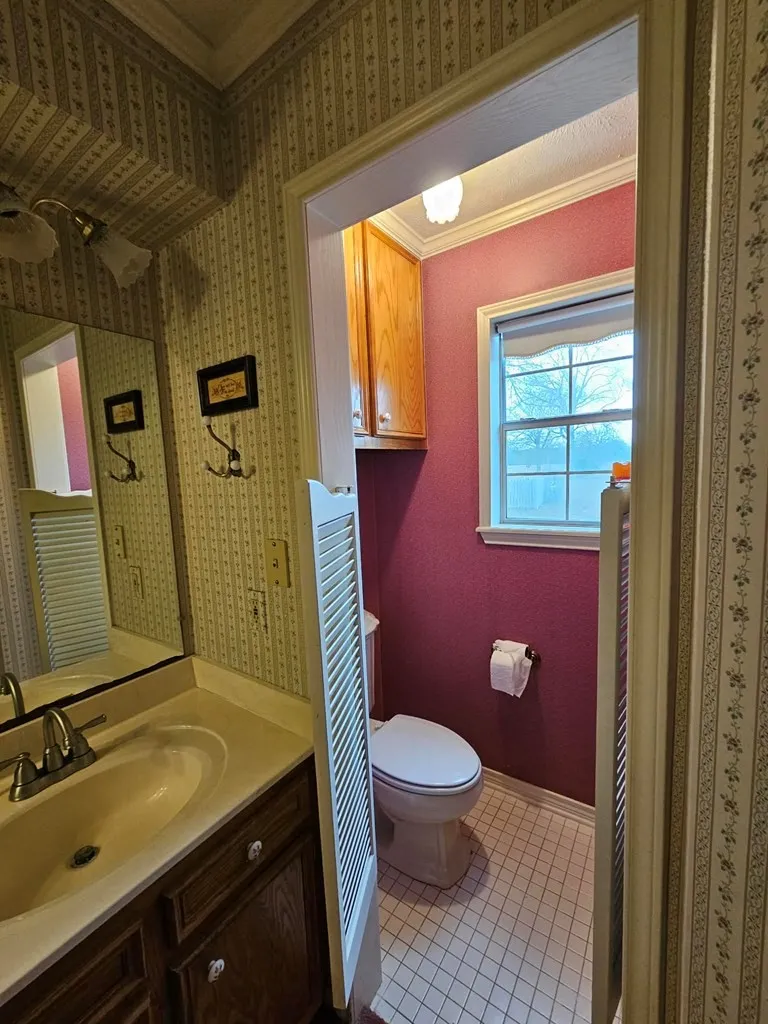 Bathroom with ornamental molding, vanity, light tile patterned flooring, a shower with shower curtain, and wallpapered walls