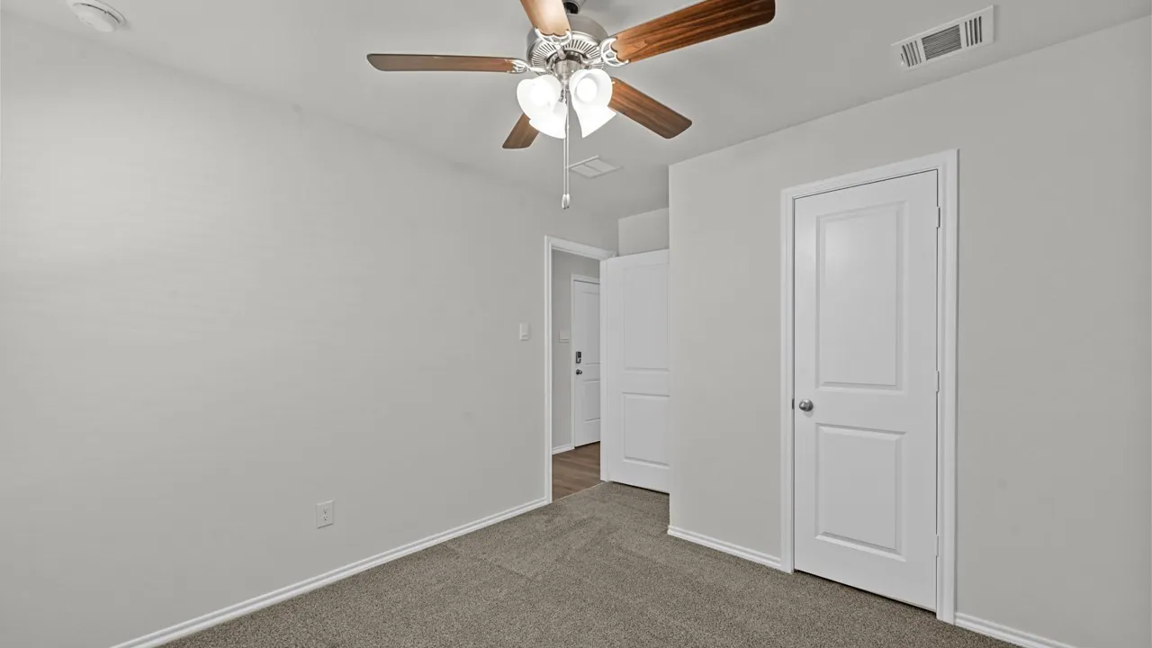 Neutral wall paint, ceiling fan with light fixture, gray carpet flooring, white trim, and white two-panel doors