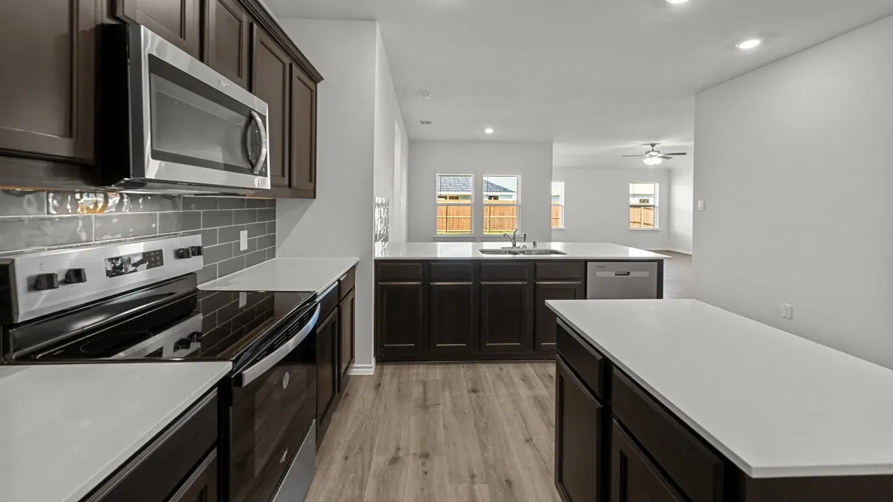 Kitchen featuring dark wood cabinetry, light countertops, wood-finish flooring, a stainless steel microwave, and a smooth-top range