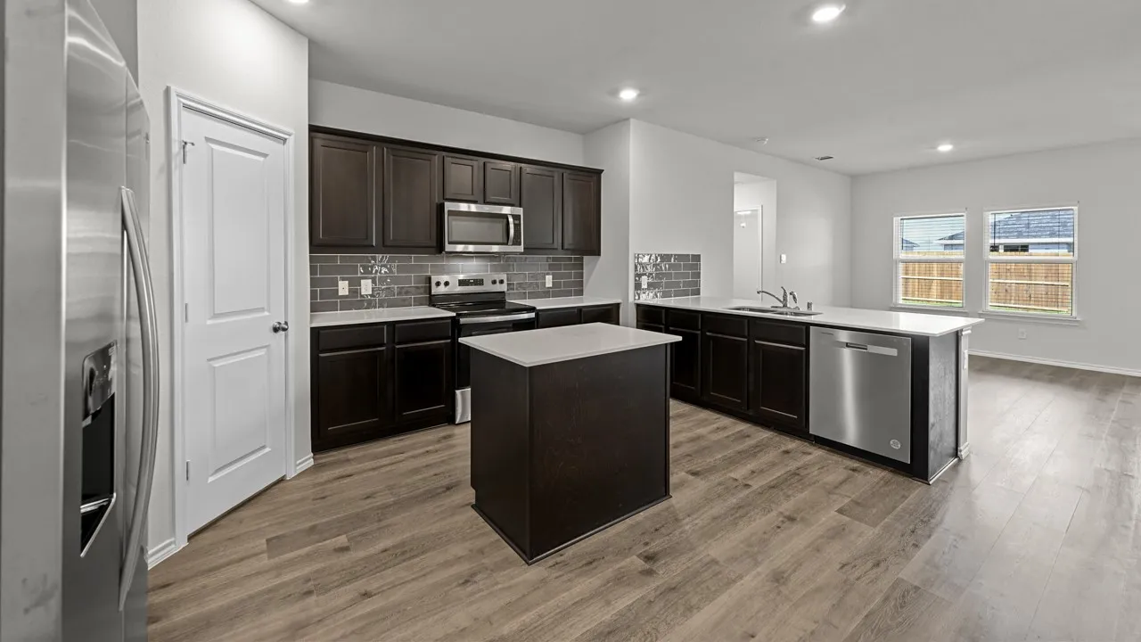 Modern kitchen featuring wood-finish flooring, dark wood cabinetry, stainless steel appliances, a center island with a light countertop, and a tile backsplash