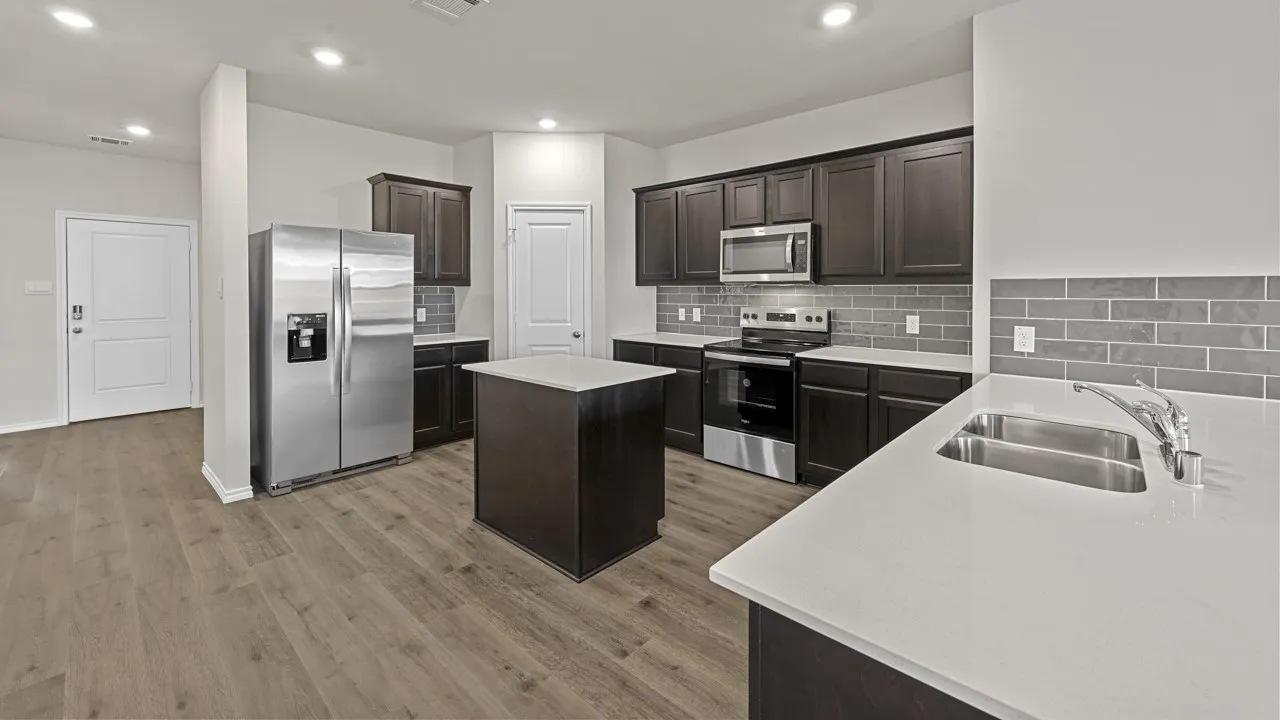 Kitchen featuring wood-finish flooring, dark wood cabinetry, light-toned countertops, a stainless steel appliance suite, and a gray subway tile backsplash