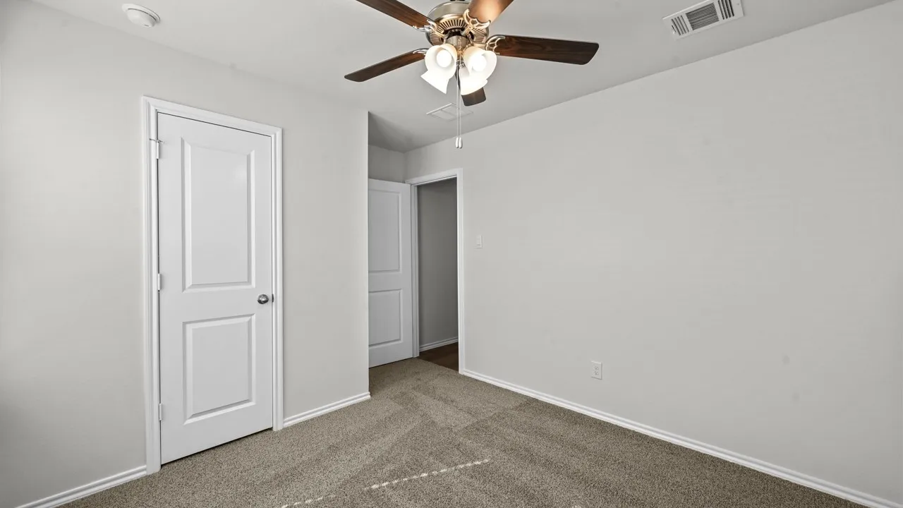 Neutral-toned room featuring light gray walls, plush carpeting, and white baseboards