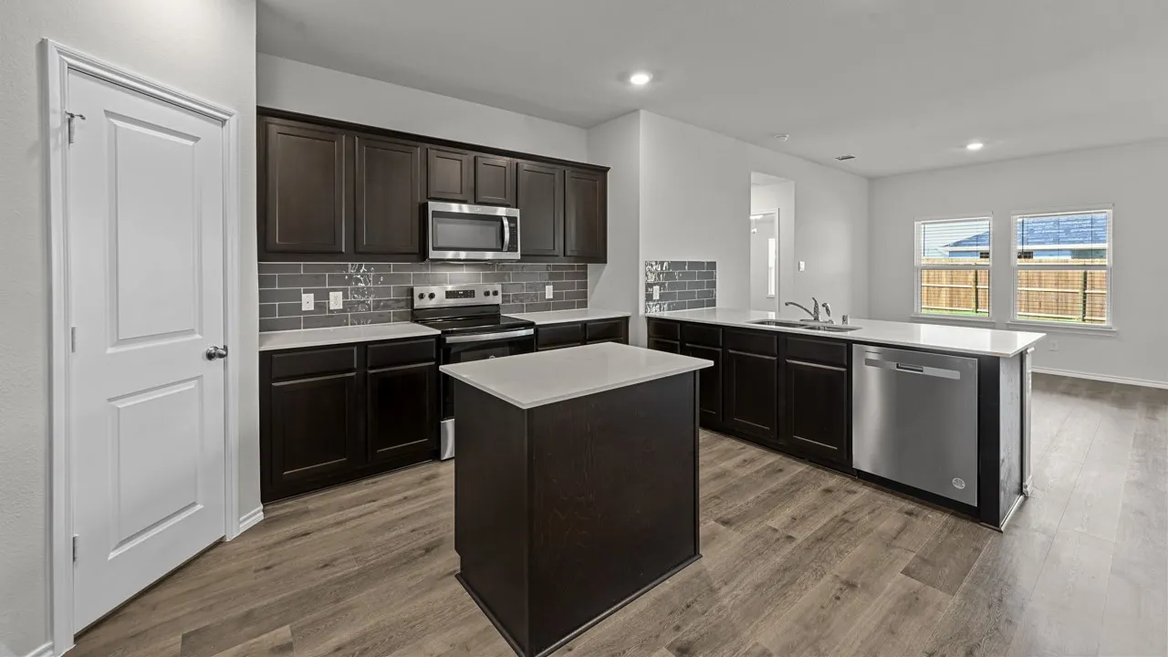 Kitchen featuring a peninsula, stainless steel appliances, dark wood finish cabinets, a center island, and tasteful backsplash