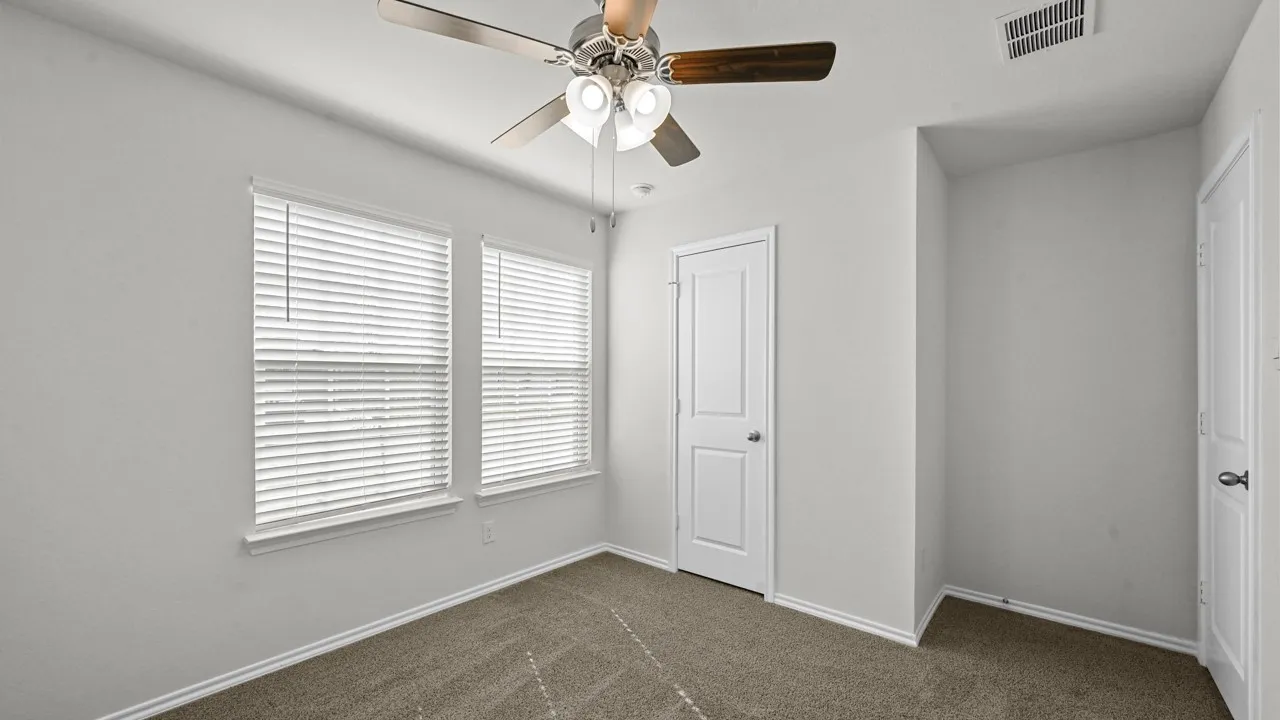 Unfurnished bedroom with dark colored carpet and ceiling fan