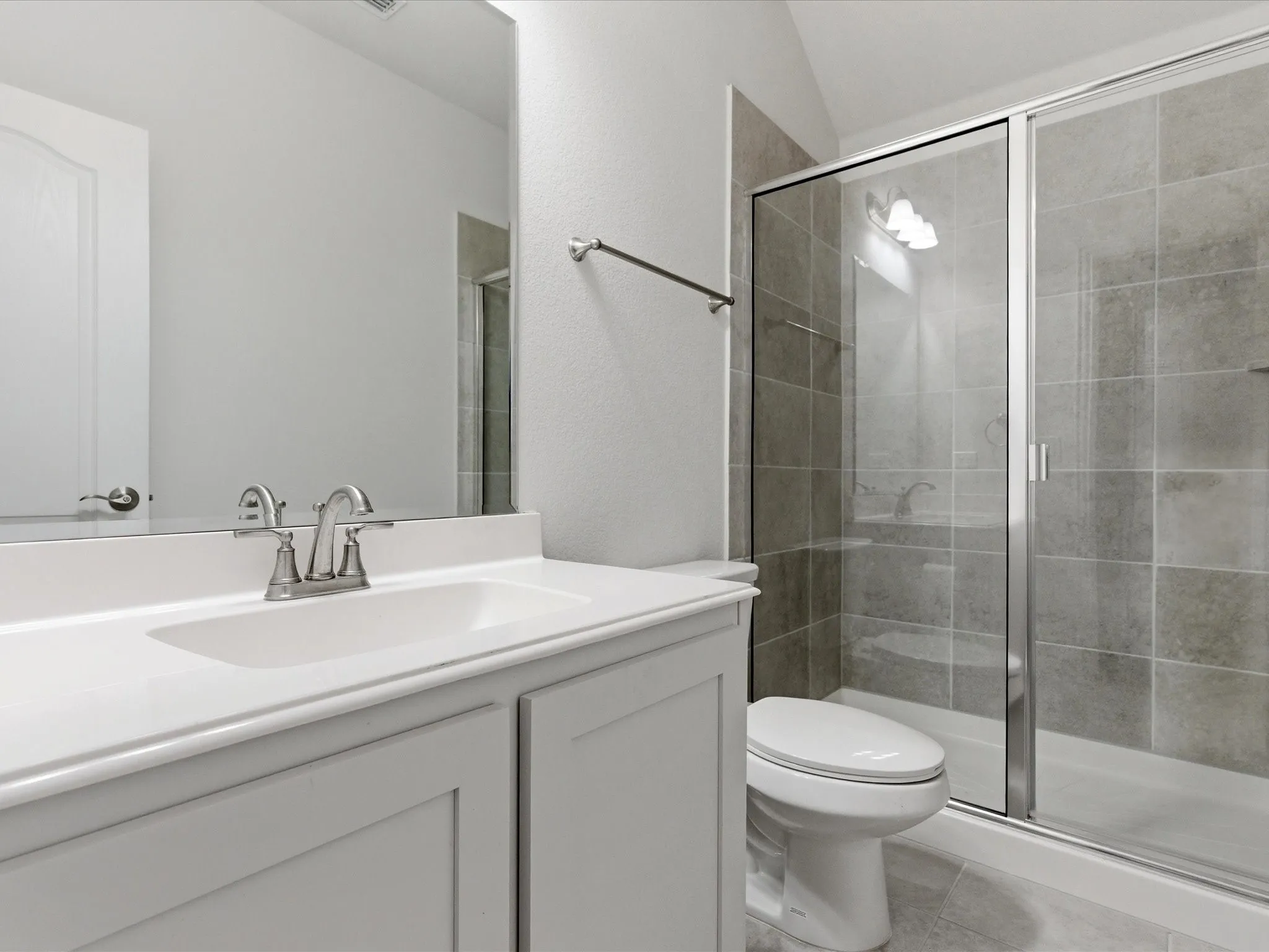 Full bath featuring vanity, a shower stall, lofted ceiling, and light tile patterned floors