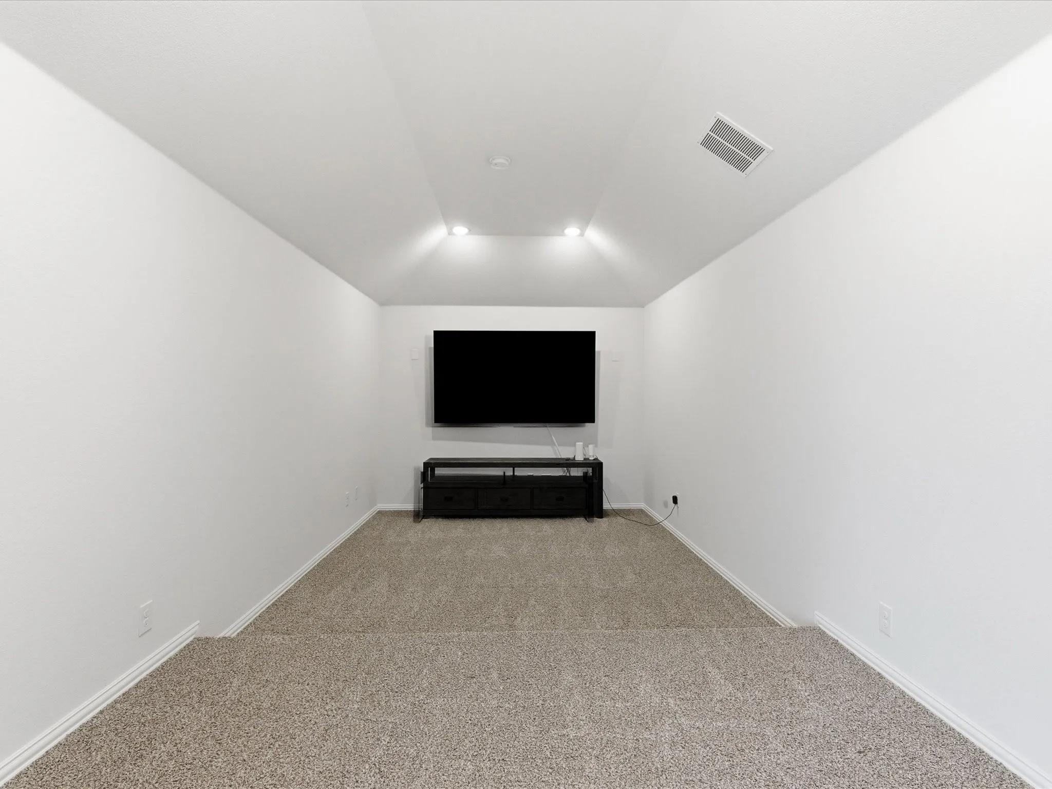 Cinema room with light colored carpet and vaulted ceiling