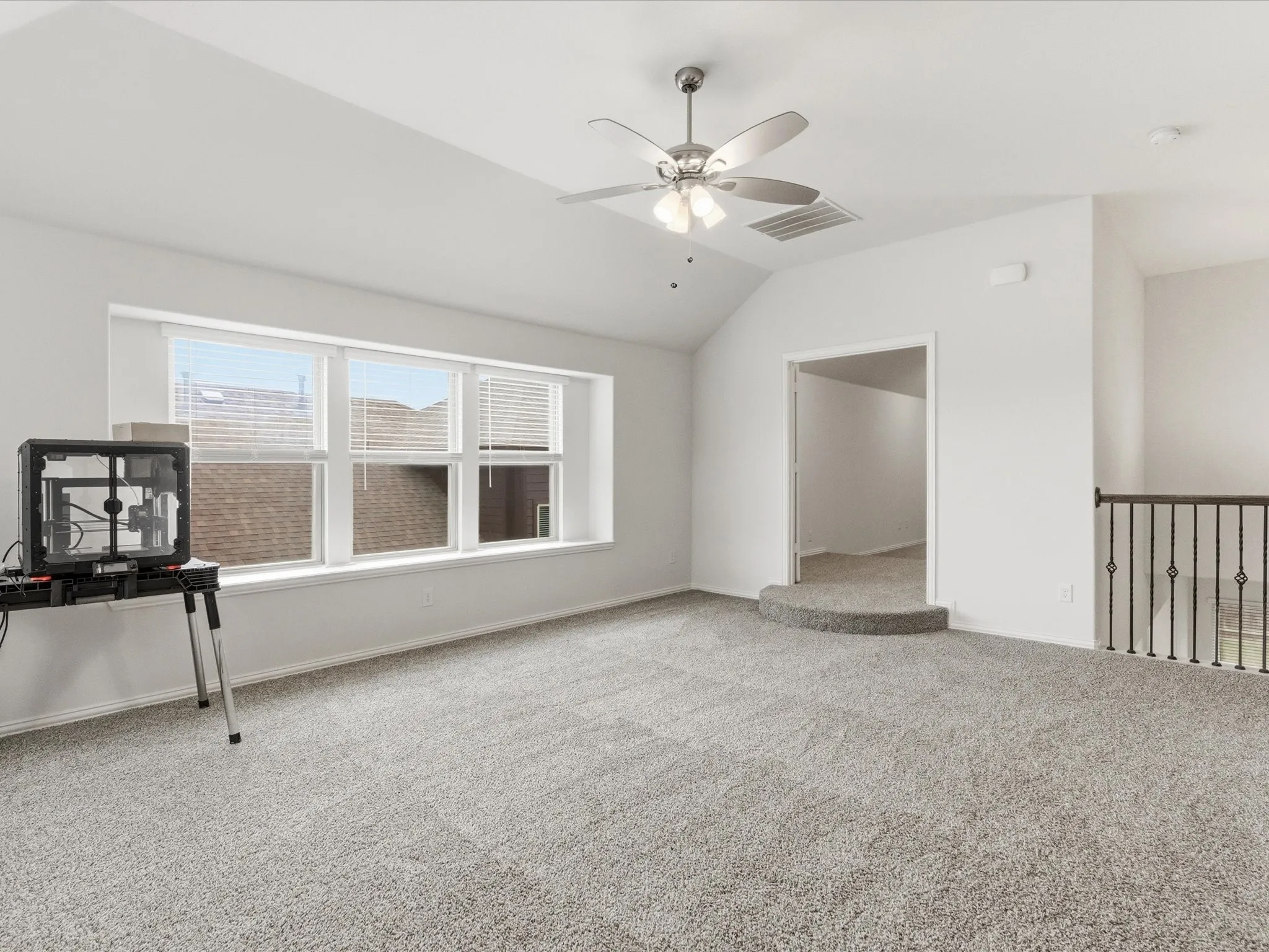 Carpeted empty room with a ceiling fan and vaulted ceiling
