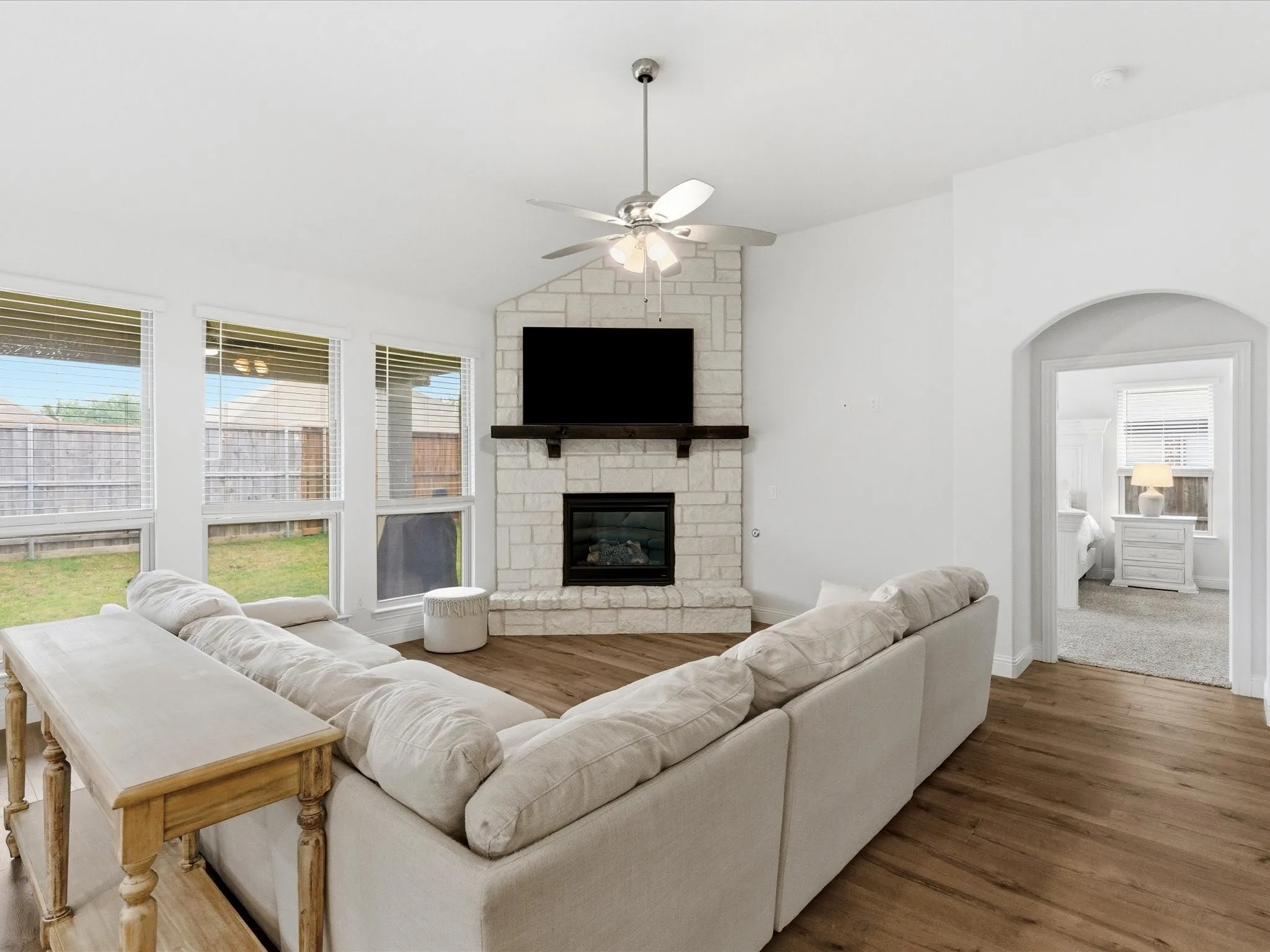 Living area featuring ceiling fan, lofted ceiling, wood finished floors, and a fireplace
