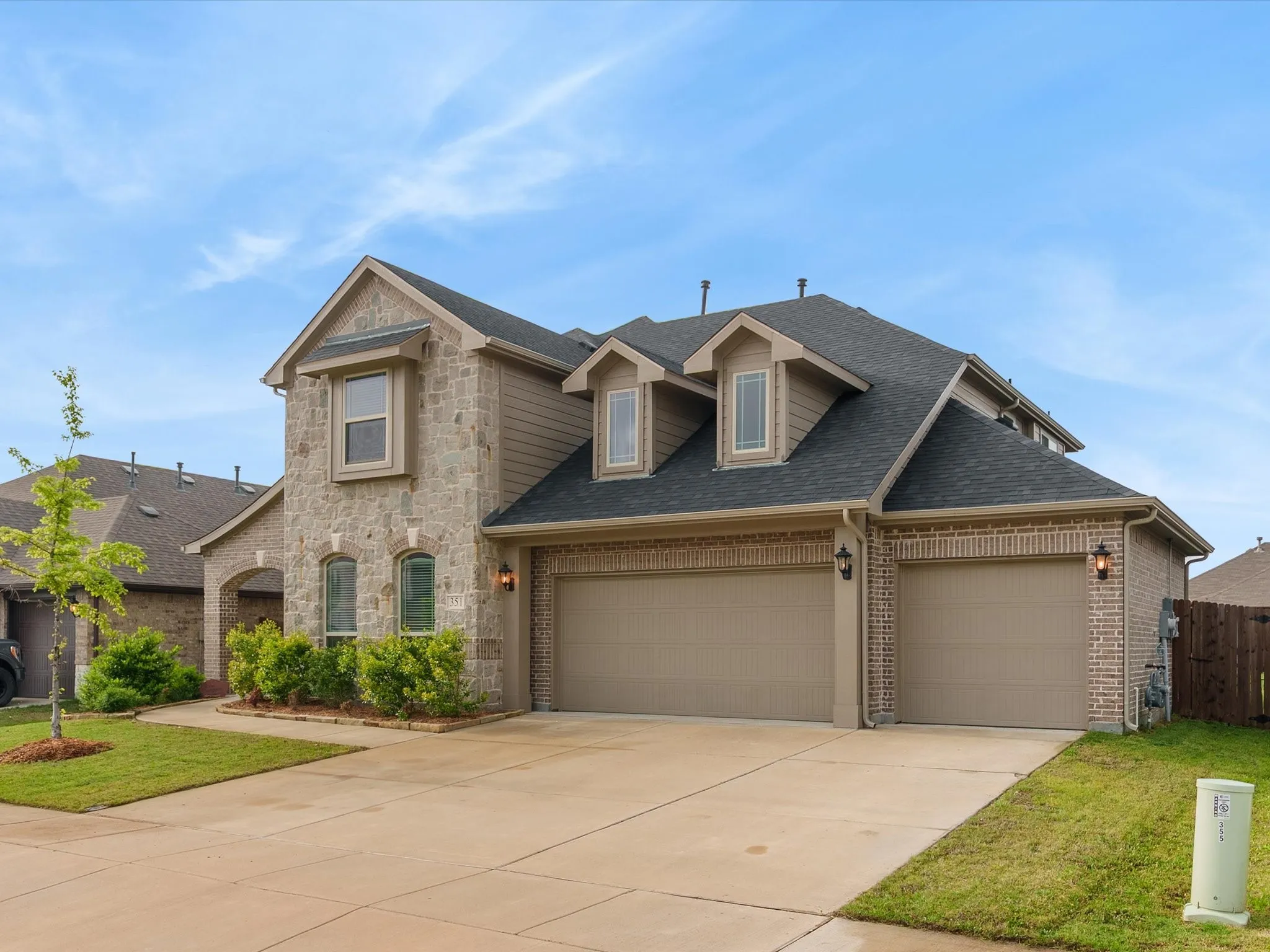 View of front of house featuring an attached garage, a shingled roof, concrete driveway, and brick siding