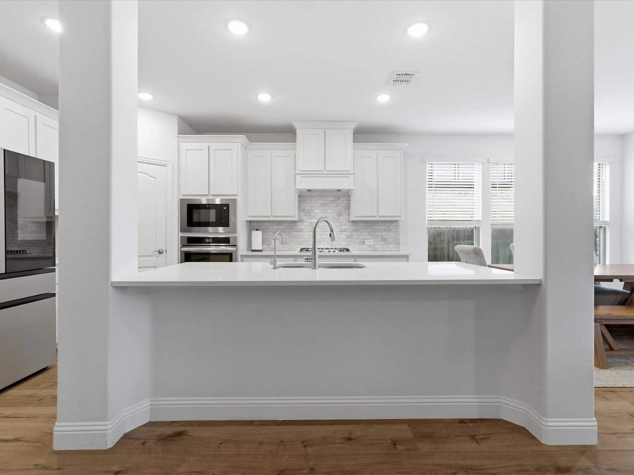 Kitchen featuring white cabinetry, dark wood-style floors, stainless steel appliances, recessed lighting, and backsplash