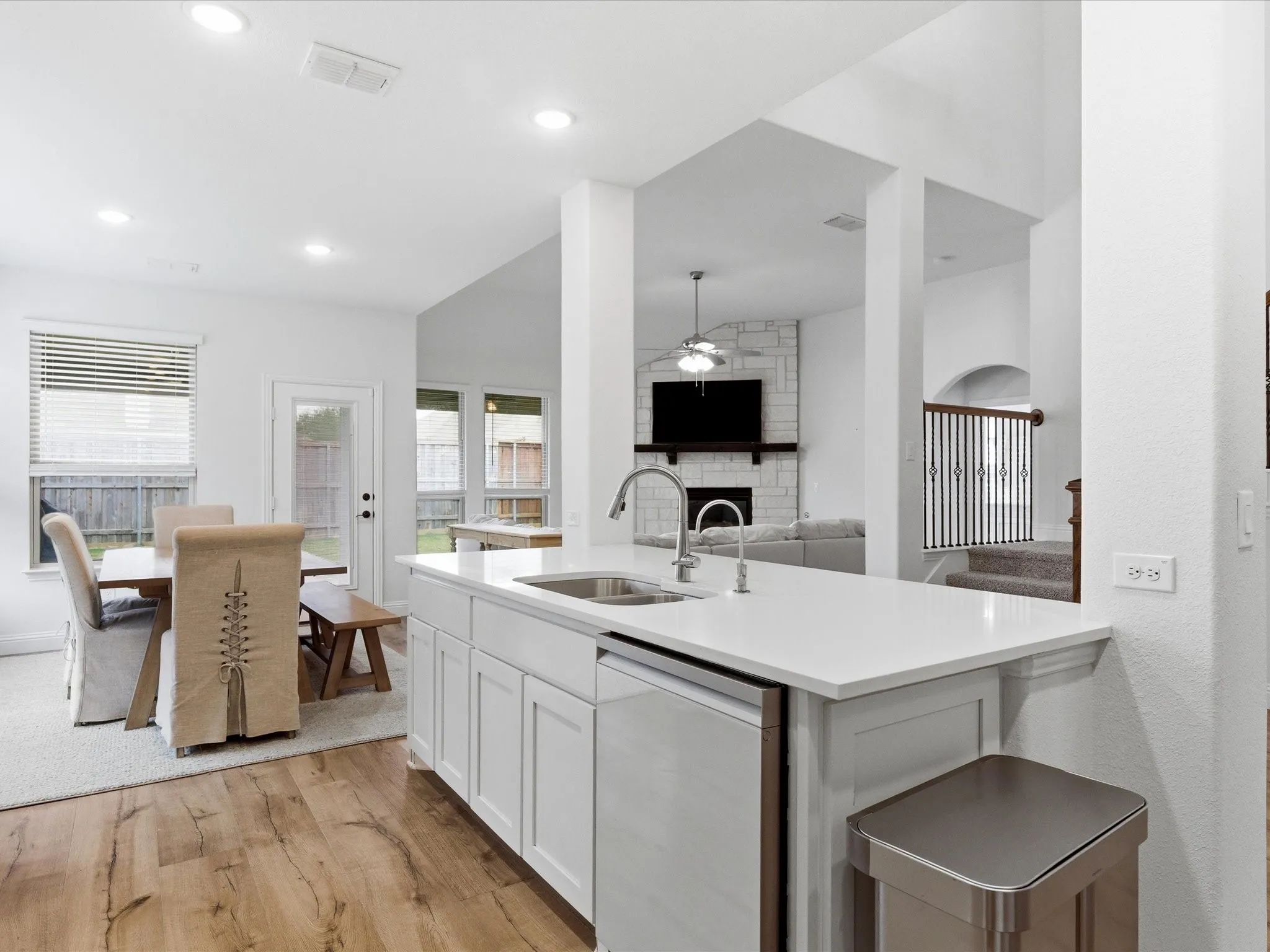 Kitchen with ceiling fan, a fireplace, dishwasher, open floor plan, and light wood-style floors