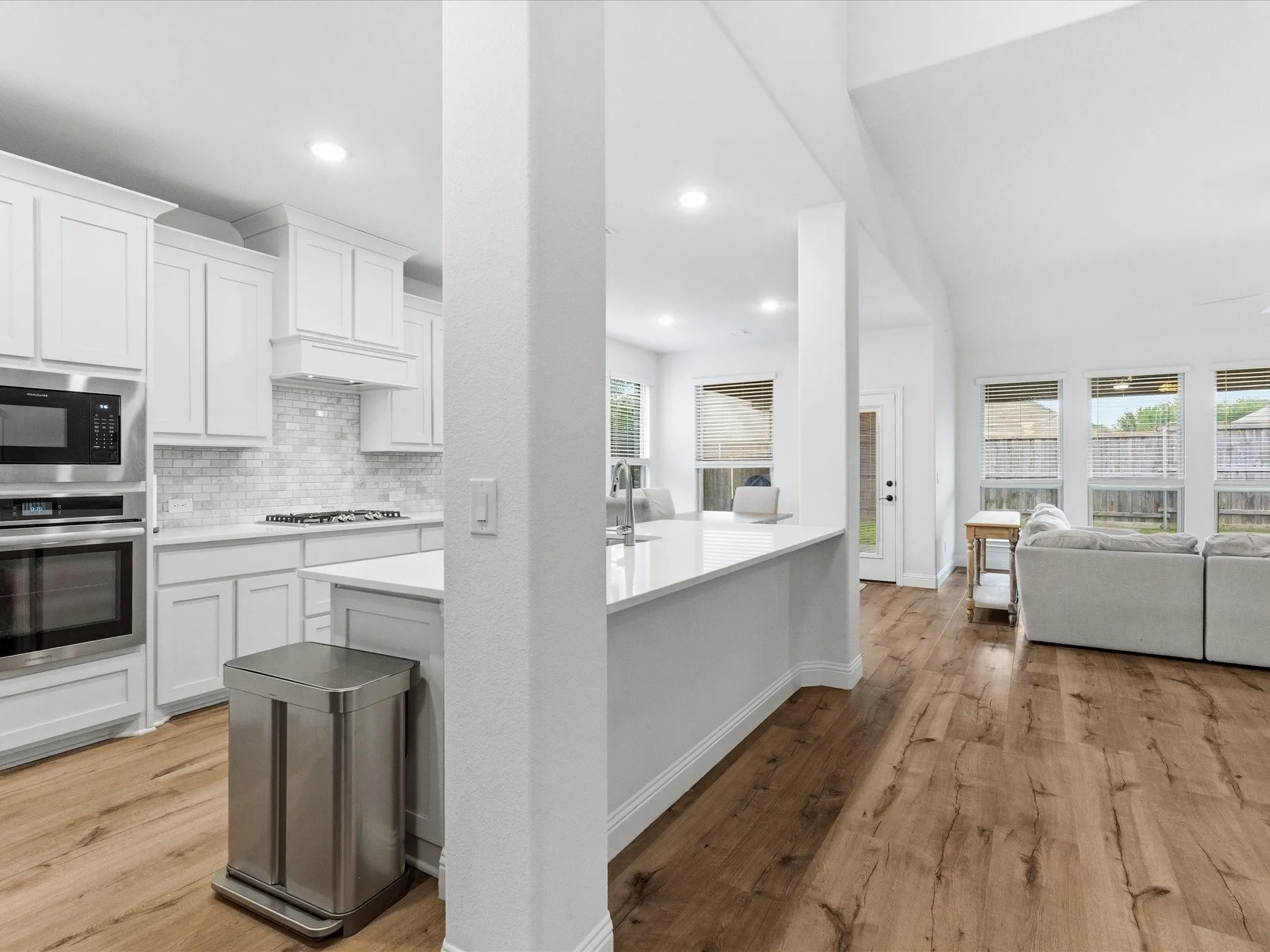 Kitchen featuring white cabinetry, stainless steel appliances, light wood finished floors, decorative backsplash, and recessed lighting