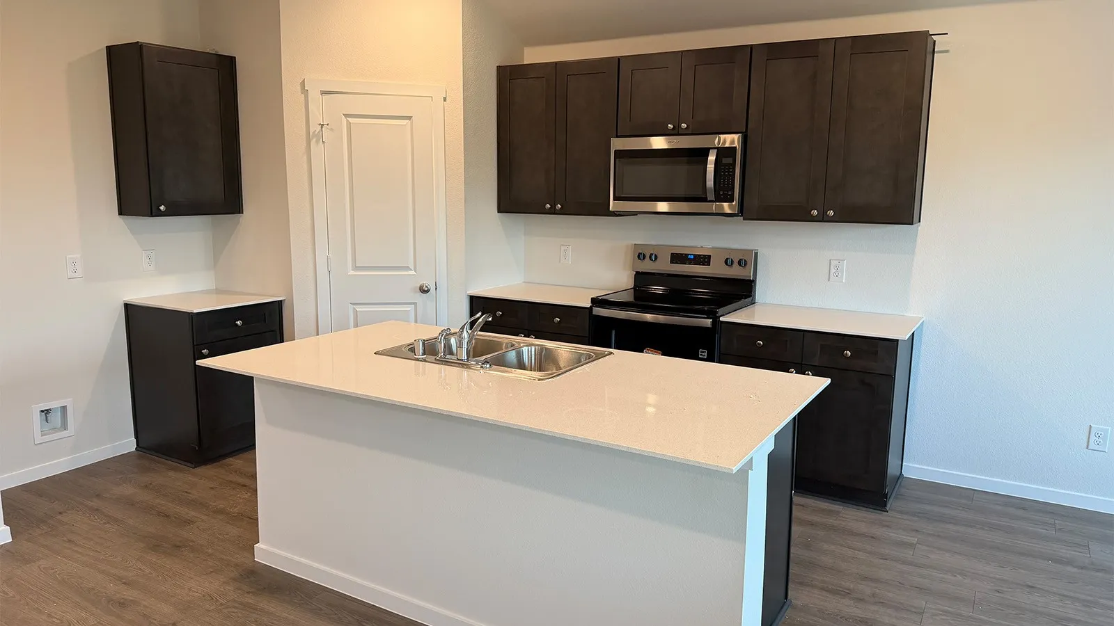 Kitchen with stainless steel appliances, dark wood finish cabinetry, a center island with sink, and dark wood-style flooring