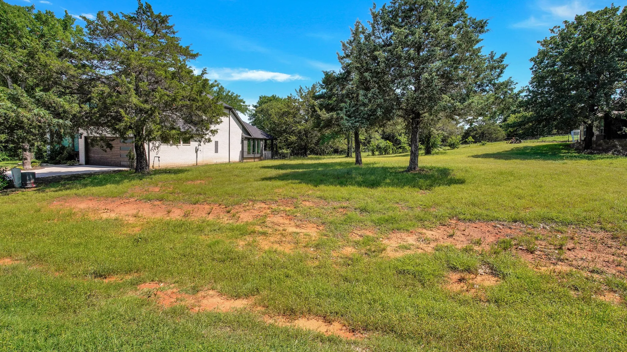 View of grassy yard with a garage and driveway