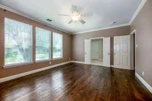 Unfurnished bedroom featuring dark wood-style flooring, crown molding, and a ceiling fan