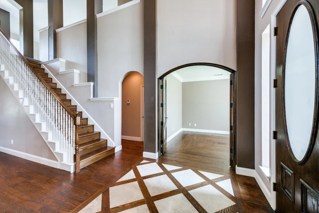 Foyer featuring arched walkways, a high ceiling, dark wood-type flooring, crown molding, and inlaid floor details