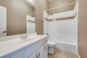 Bathroom with vanity, washtub / shower combination, and light tile patterned flooring