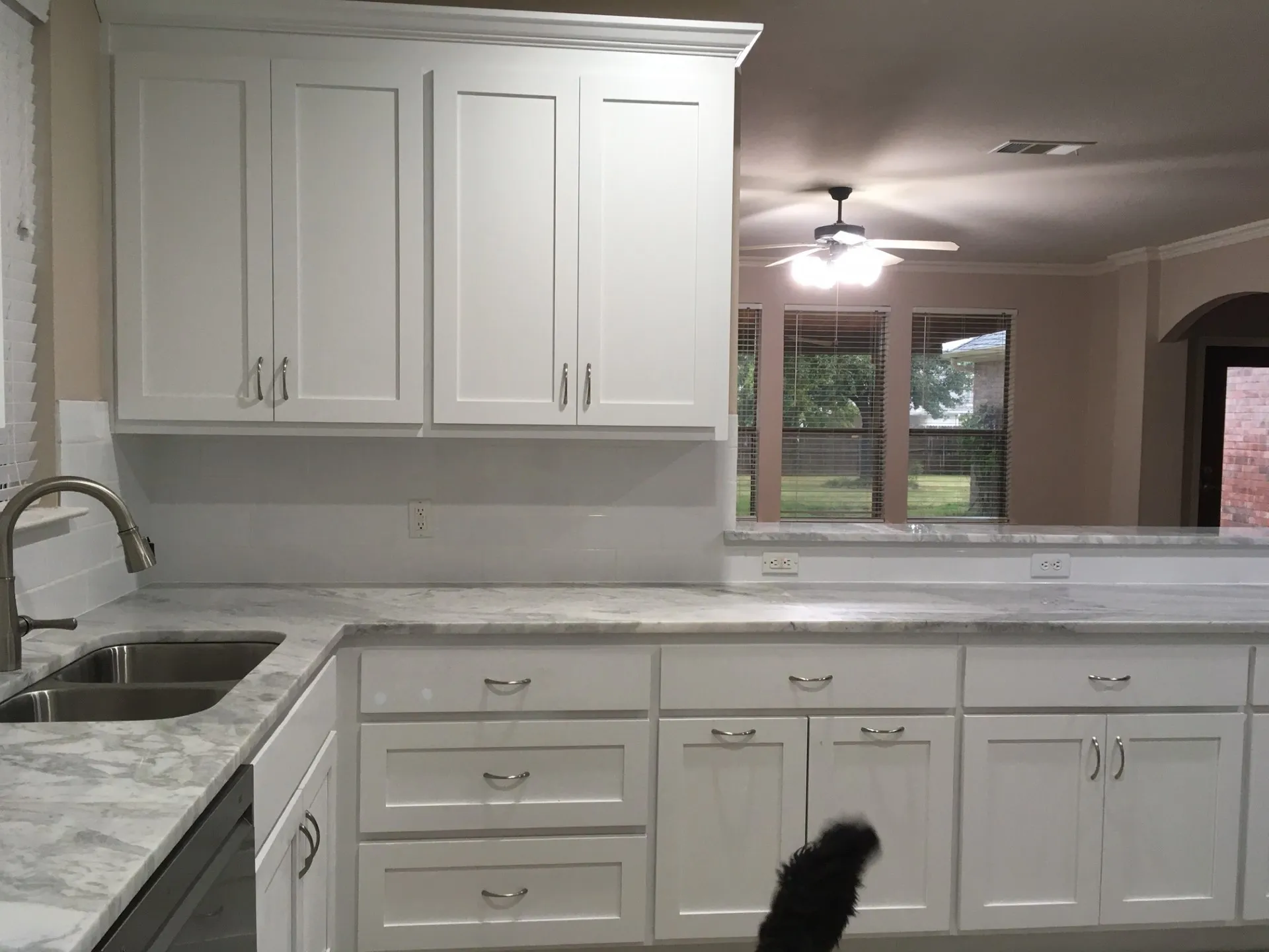 Kitchen with white cabinetry, light stone counters, dishwasher, ceiling fan, and crown molding