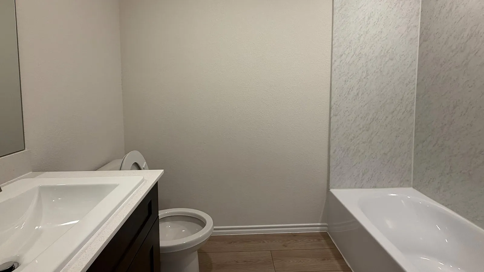 Modern bathroom featuring a sleek white vanity with integrated sink, ceramic tile flooring, and frameless glass shower enclosure