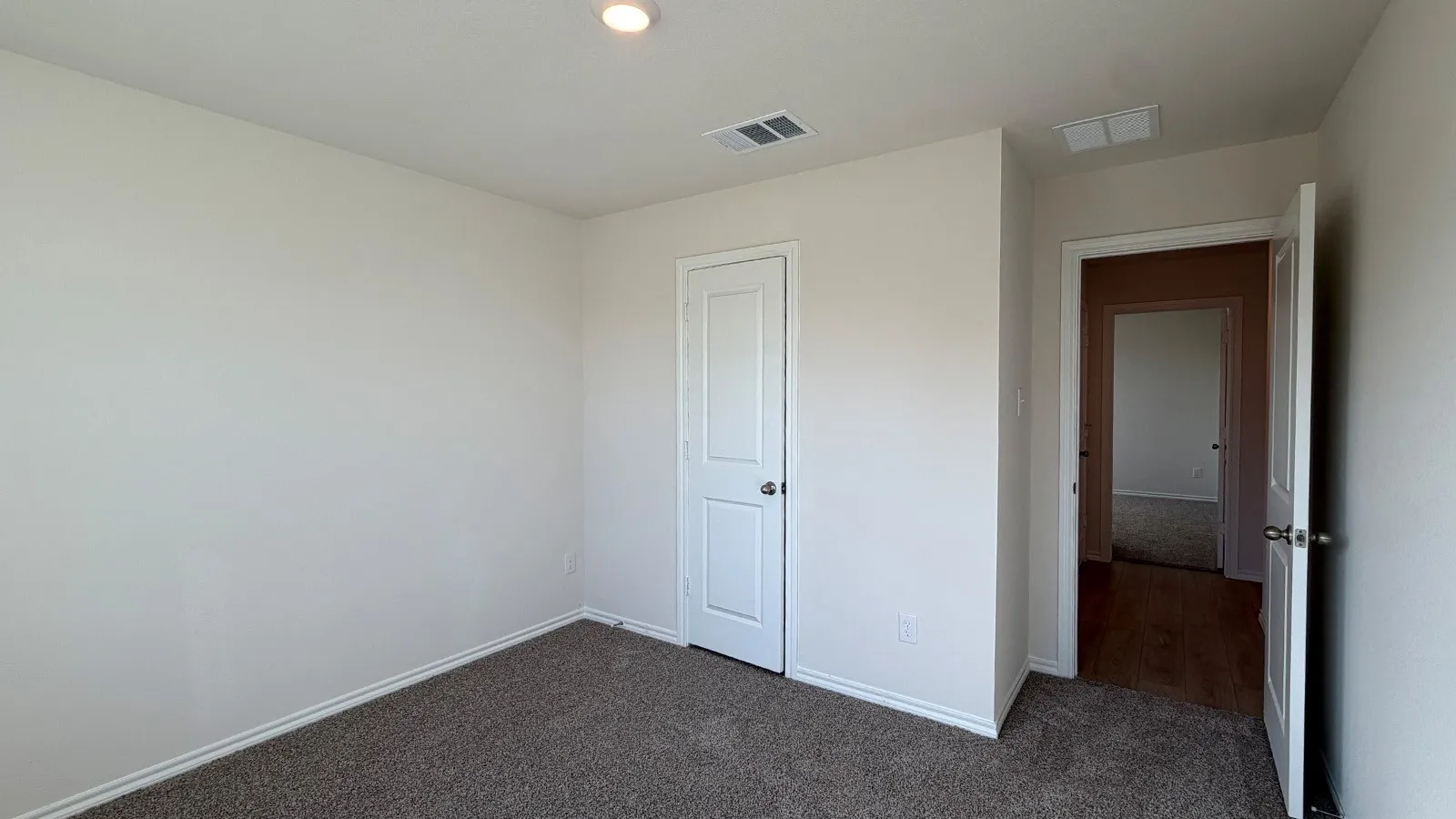 Neutral wall finishes, recessed ceiling lighting, and dark carpet flooring