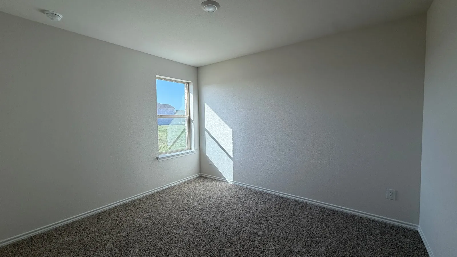 Room featuring neutral-toned walls, carpeted flooring, and a single window offering exterior views