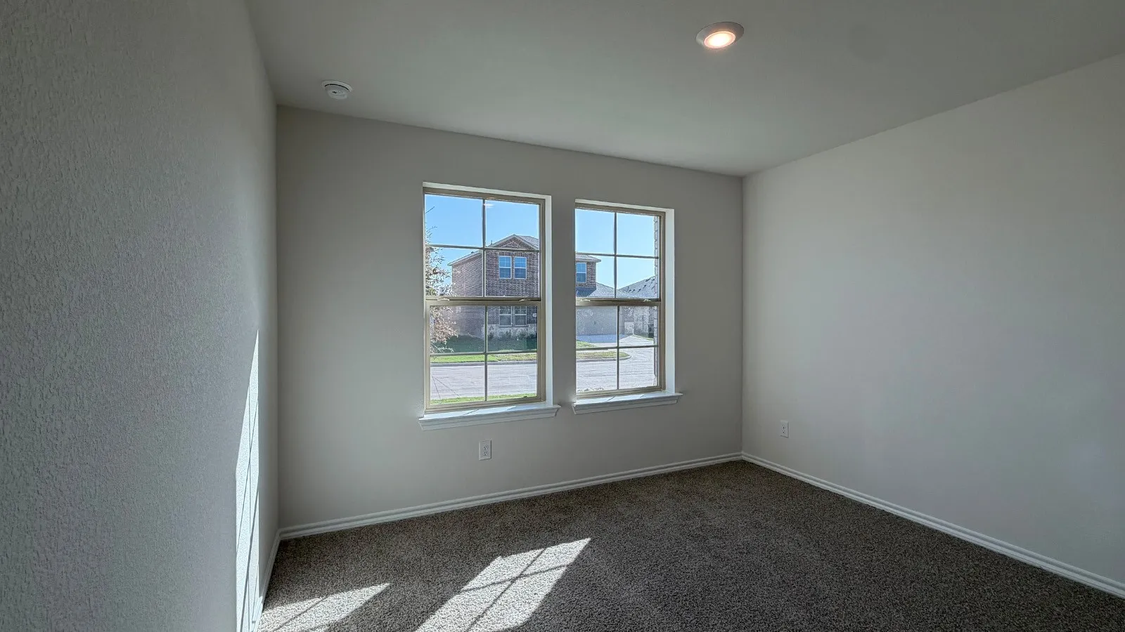 Carpeted room featuring two prominent windows, white trim, and a recessed ceiling light