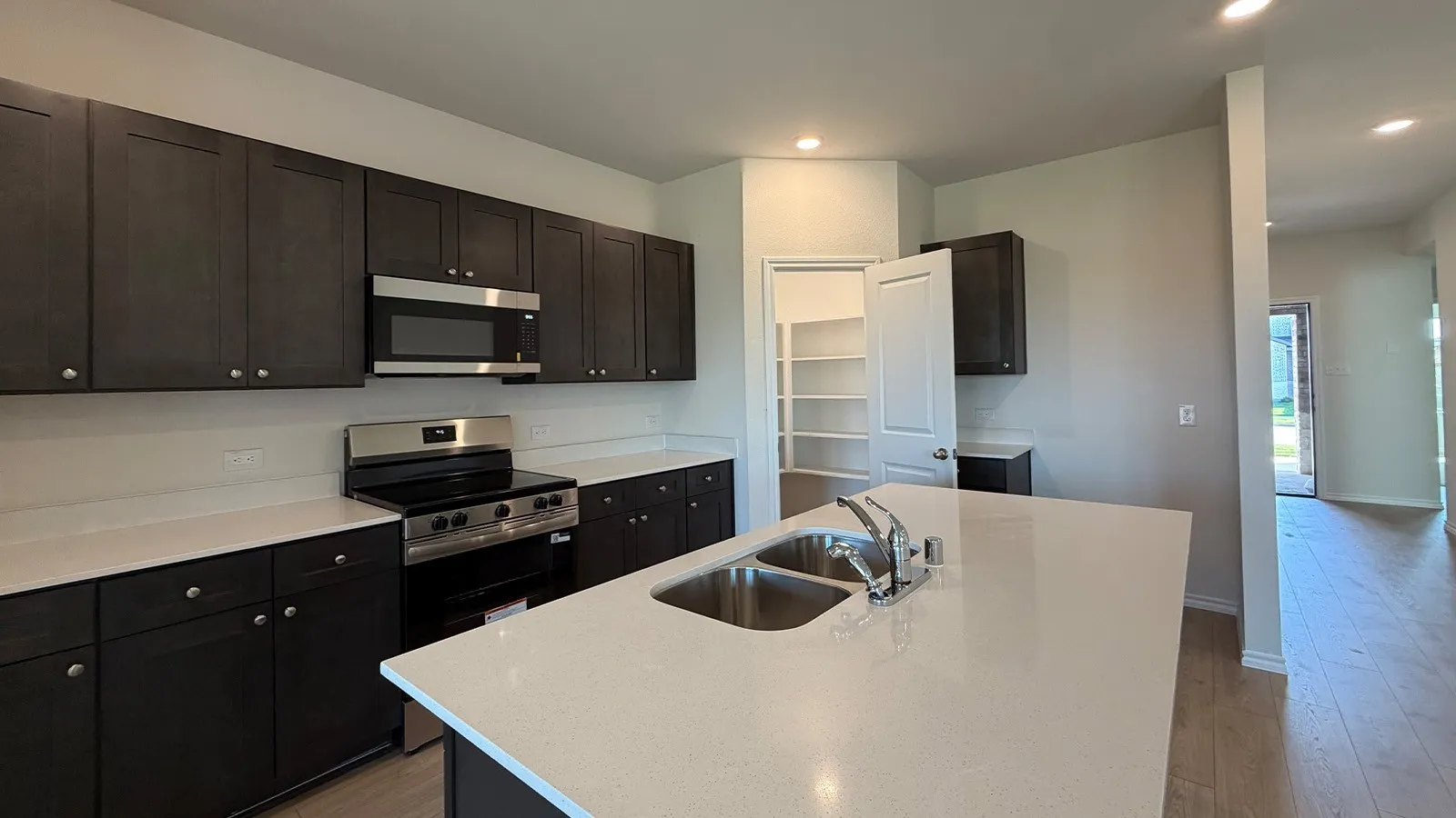 Modern kitchen featuring dark wood-finish cabinetry, stainless steel appliances, and light-colored countertops