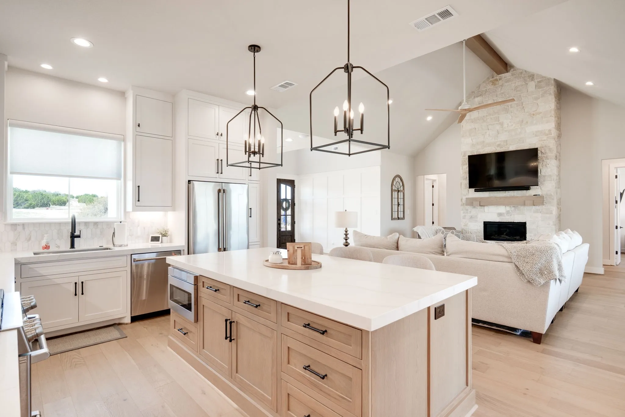 Dual tone kitchen with built in appliances, light wood-type flooring, a center island, open floor plan, and a fireplace