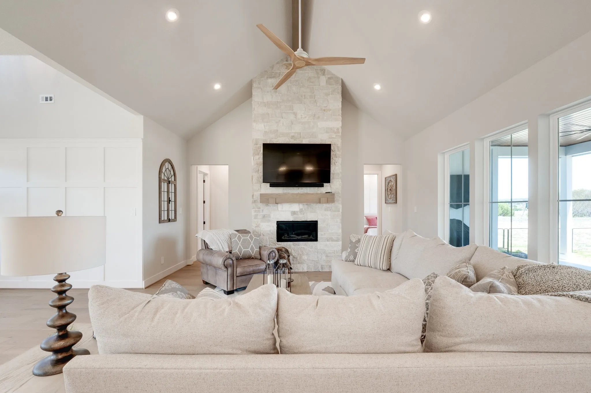 Living room with light wood-type flooring, ceiling fan, and a stone fireplace
