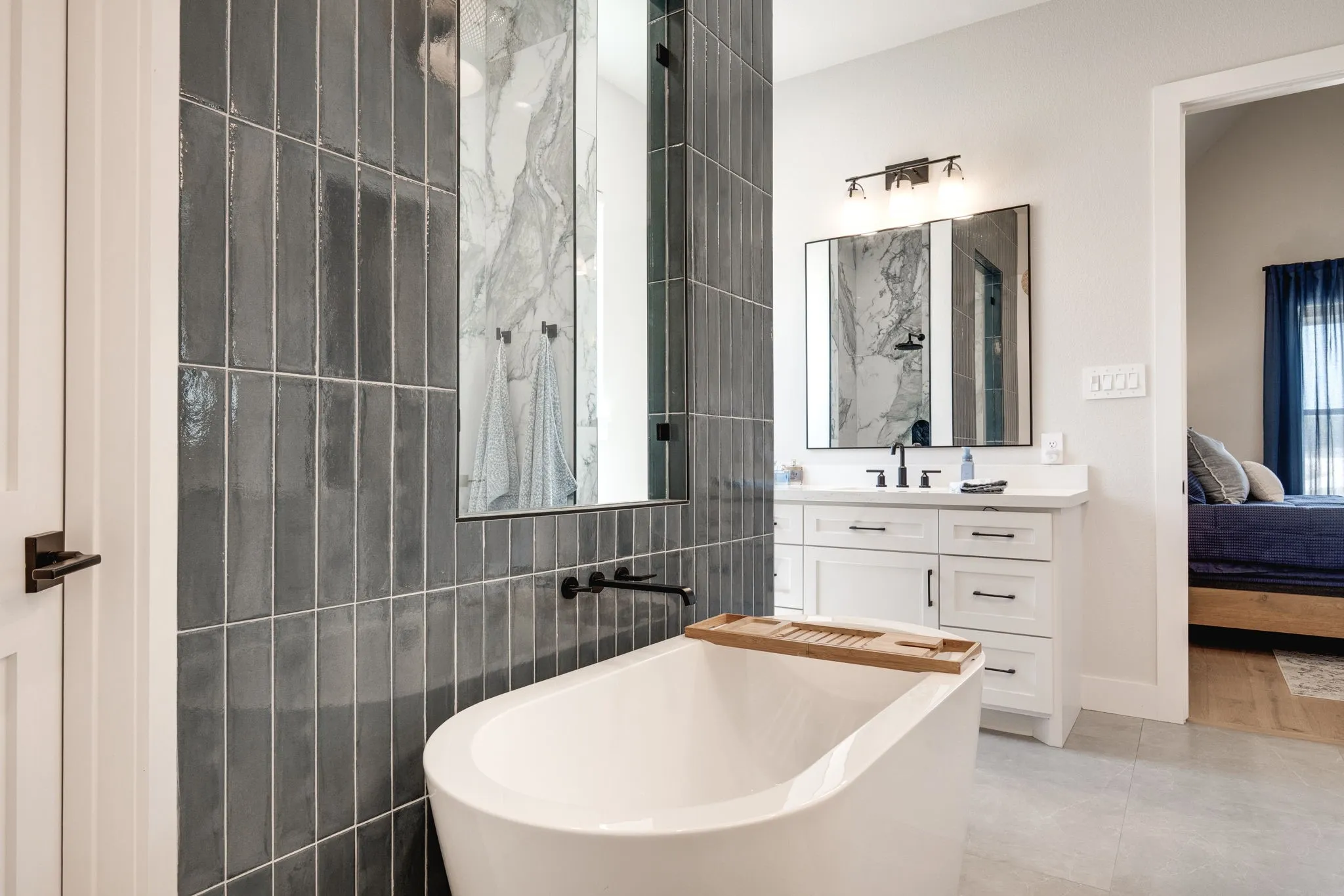 Ensuite bathroom with vanity, a freestanding bath, tile walls, light tile patterned floors, and a marble finish shower