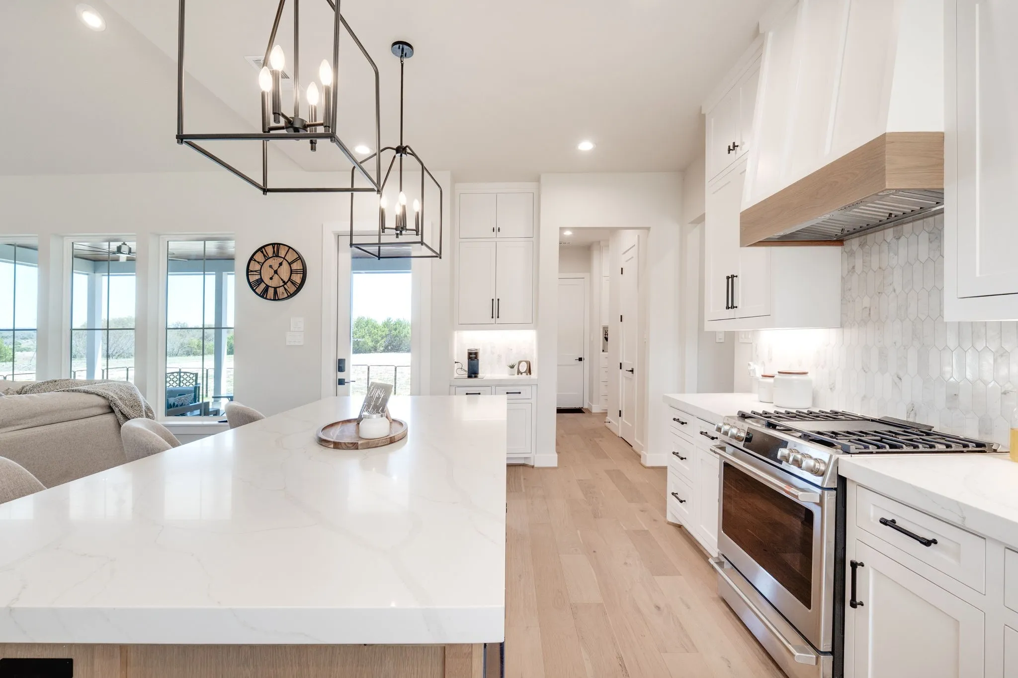 Kitchen with stainless steel gas range, a chandelier, tasteful backsplash, light wood finished floors, and white cabinets