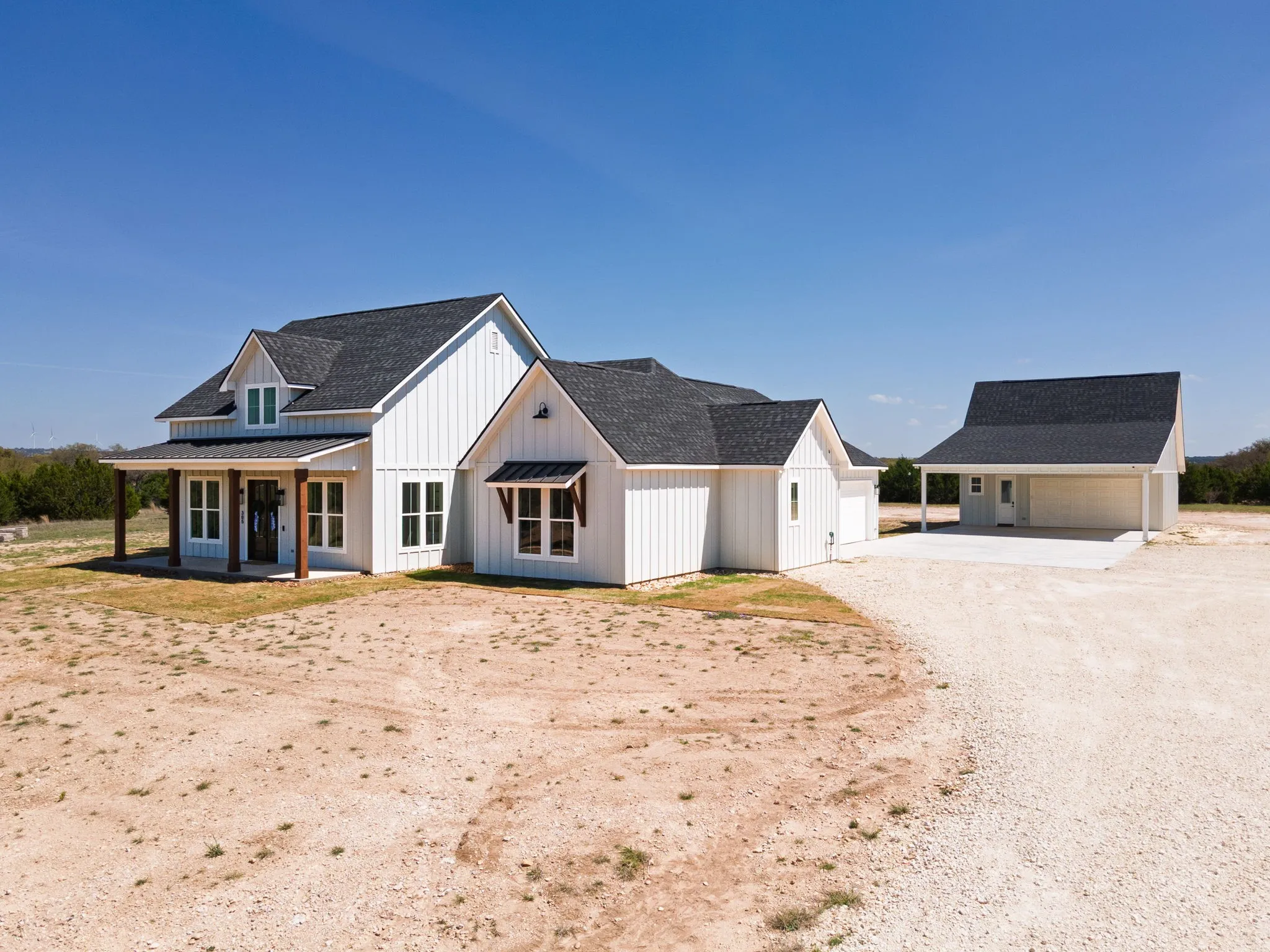 Modern farmhouse style home with an outbuilding, roof with shingles, driveway, and a porch