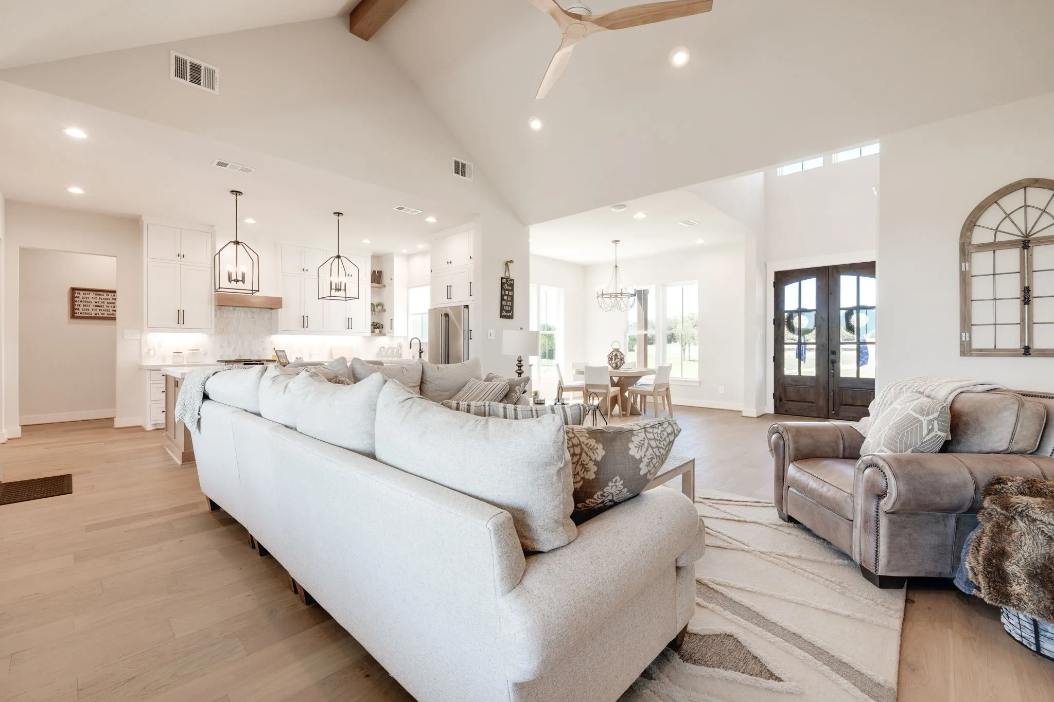 Living area with light wood finished floors, hanging lights, a ceiling fan, and french doors
