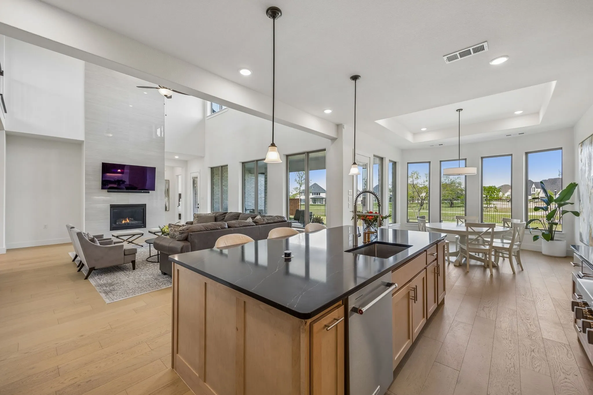 Kitchen with a kitchen island with sink, plenty of natural light, open floor plan, light wood-style floors, and a raised ceiling
