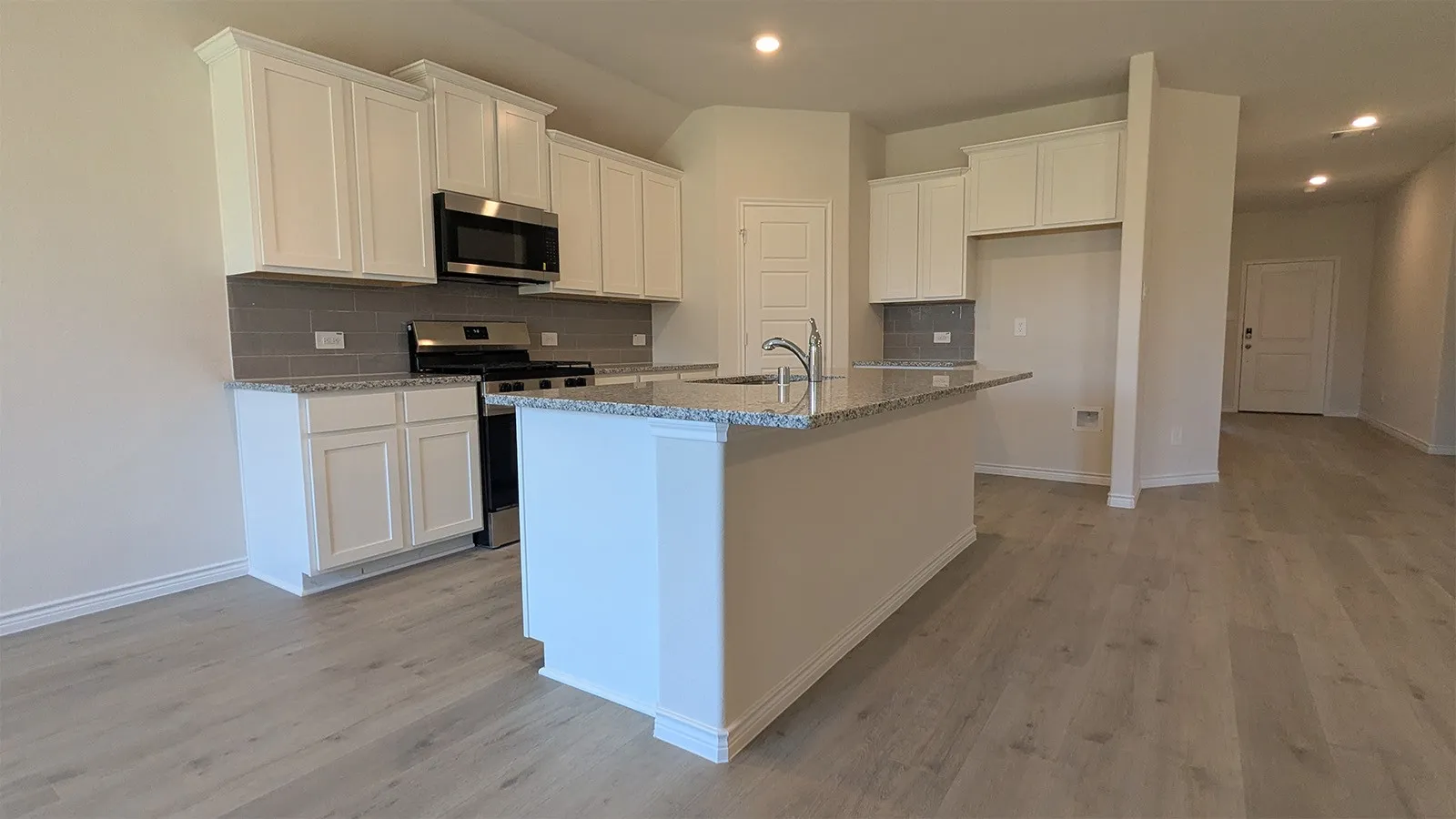 Kitchen featuring white shaker-style cabinetry, granite countertops, a stainless steel gas range, and a subway tile backsplash