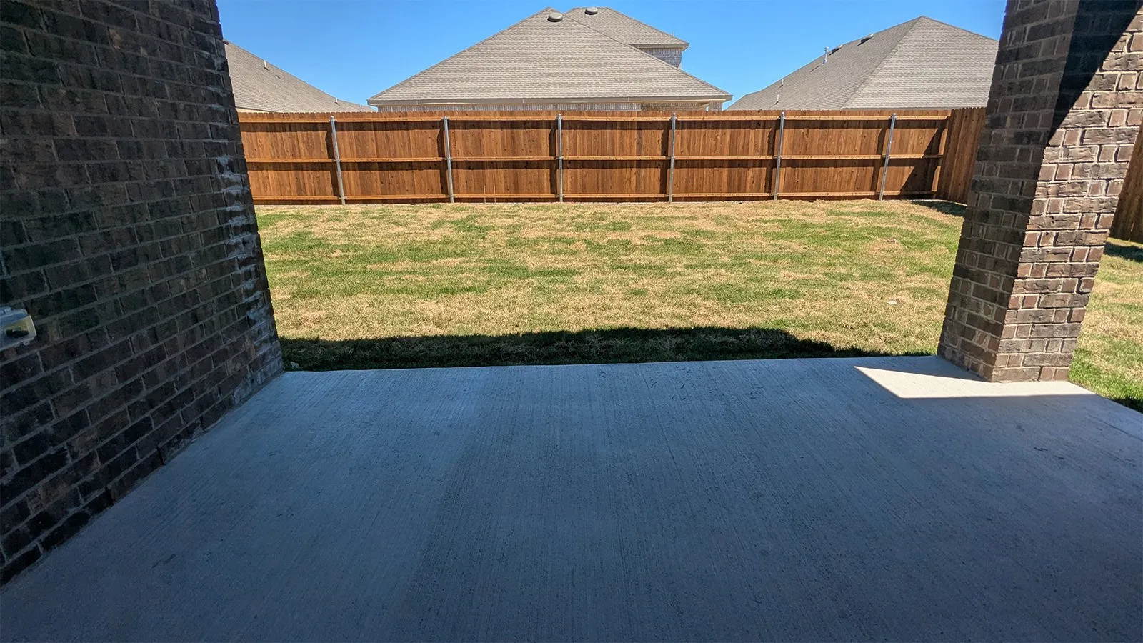 Expansive concrete patio with brick pillars, offering an outdoor living area