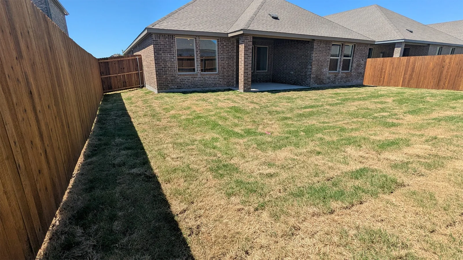 Fenced backyard featuring a covered patio, brick exterior, and a privacy fence