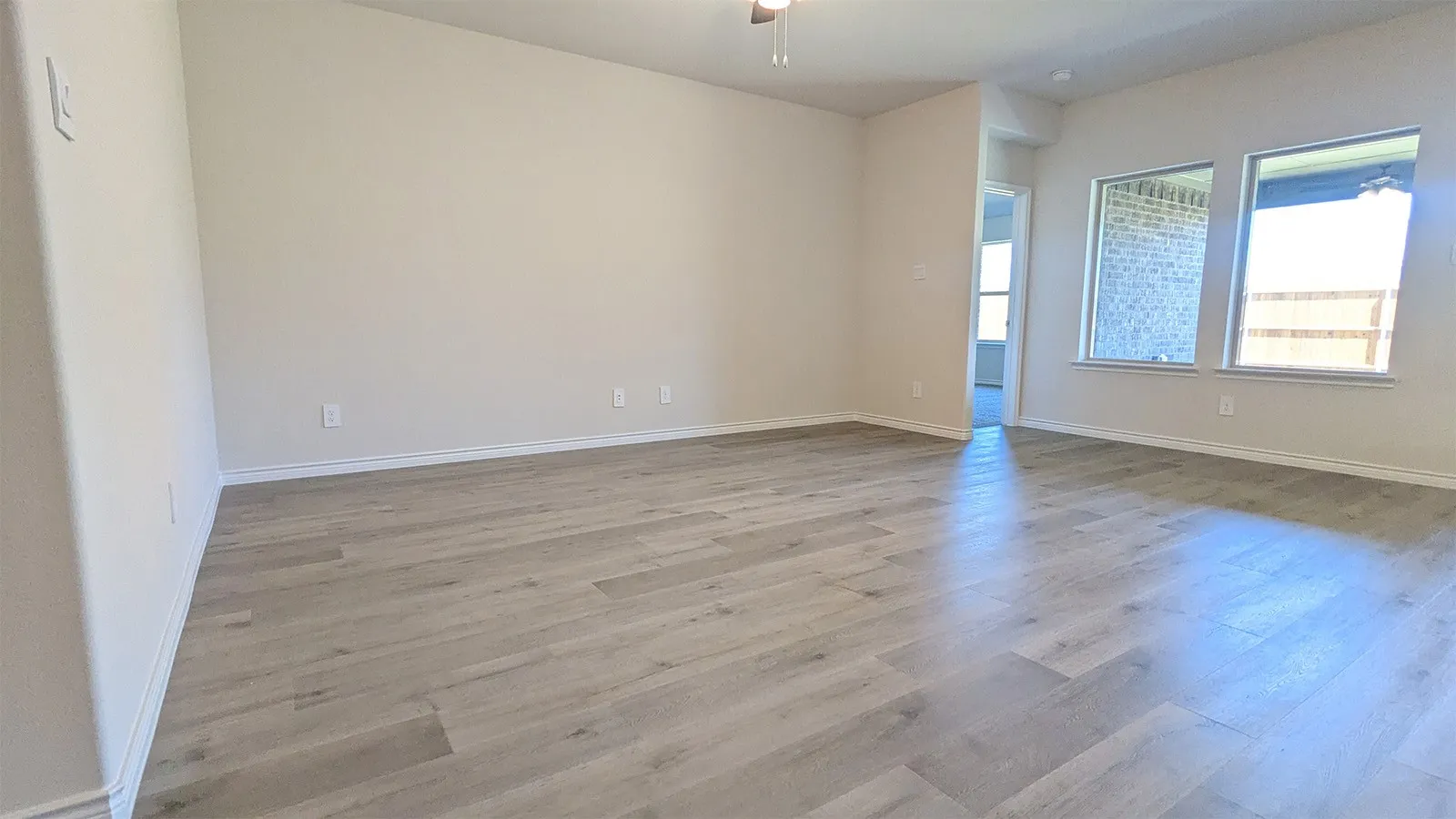 Spacious room featuring light wood-finish flooring and neutral wall tones