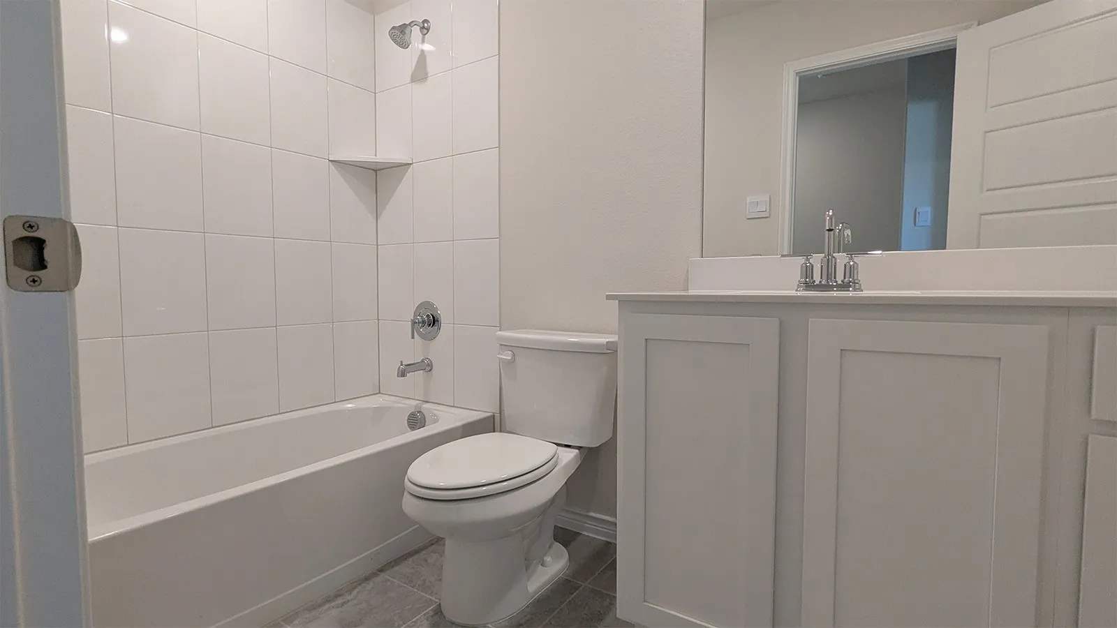 Bathroom featuring a white bathtub with subway tile surround, a built-in shower niche, and chrome fixtures