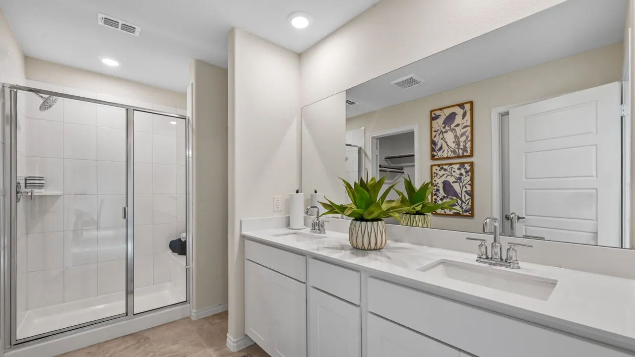 Bathroom featuring double vanity, a stall shower, and light tile patterned floors