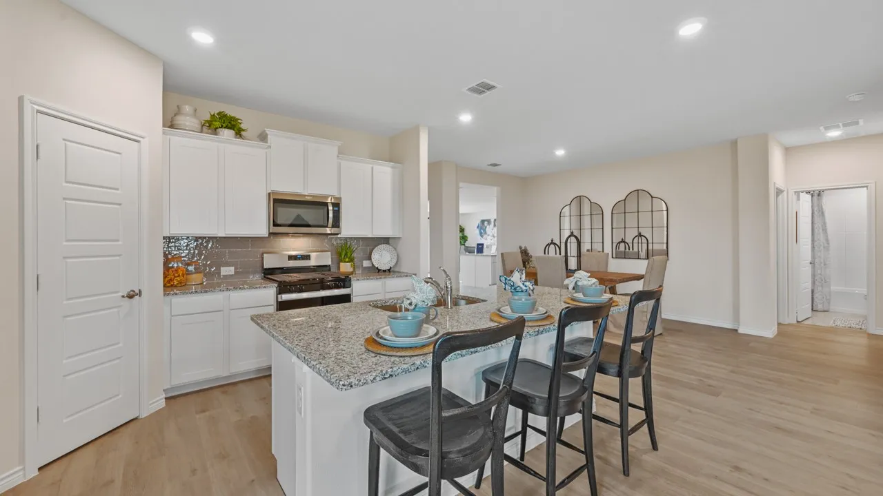 Kitchen featuring a kitchen breakfast bar, white cabinets, stainless steel appliances, light wood-style flooring, and recessed lighting